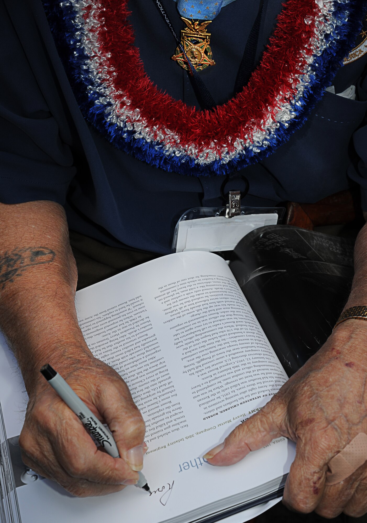 Sgt. 1st Class (Ret.) Ronald Rosser, a U.S. Army veteran of the Korean War and a Medal of Honor recipient, autographs a Medal of Honor book for Col. Johnny Roscoe’s son, along with three other Medal of Honor recipients who visited Joint Base Pearl Harbor-Hickam, Hawaii, Oct. 4. Rosser was a corporal when he performed the actions that earned him his medal on the side of a snow-covered hill in 1952. (U.S. Air Force photo/Senior Airman Lauren Main)