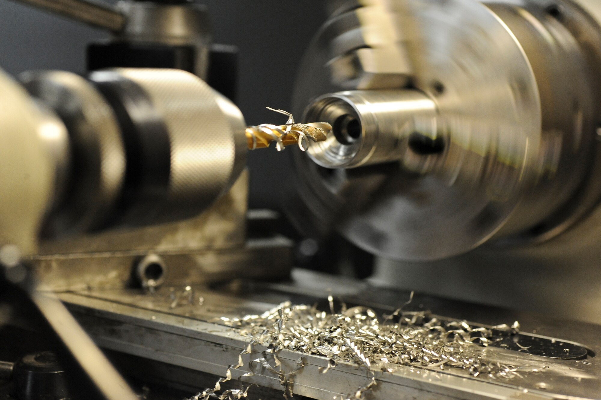 A drill bit covered in metal shavings is pulled out from a lathe on Barksdale Air Force Base, La., Oct. 4. Lathes are used to cut, sand and drill items by rotating the item by its axis. The lathe was used to bore a hole through a weapons pylon bushing. (U.S. Air Force photo/Senior Airman Micaiah Anthony)(RELEASED) 
