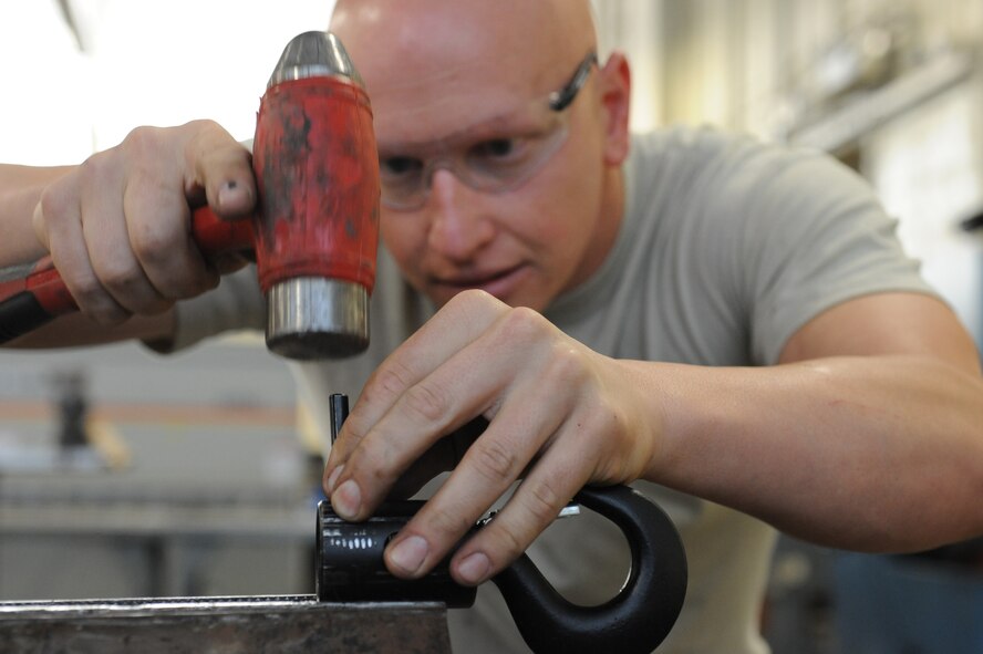 Staff Sgt. John Landers, 2nd Maintenance Squadron aircraft structural maintenance floor chief, hammers a pin through a drag chute bucket hoist chain on Barksdale Air Force Base, La., Oct. 4. The chain is used as a part of a pulley system to help Airmen lift a 185 pound drag chute off the ground. Team Barksdale is comprised of dedicated individuals who are highly trained, well-equipped and ready to work with the nation's most powerful weapon system to the level of perfection the American people expect and deserve. (U.S. Air Force photo/Senior Airman Micaiah Anthony)(RELEASED)