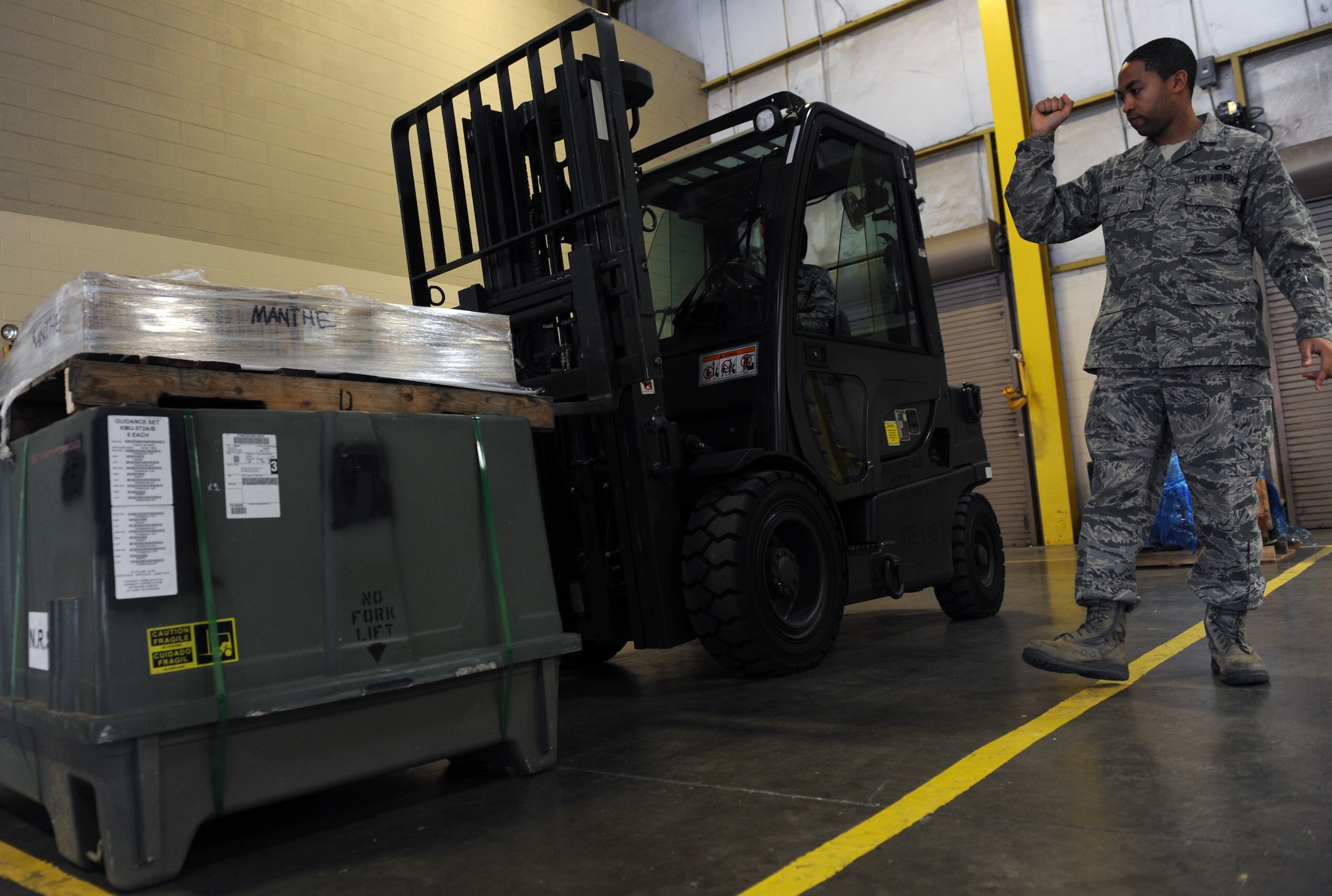 WHITEMAN AIR FORCE BASE, Mo. -- Staff Sgt. Tarae Day, 509th Logistics Readiness Squadron in-bound cargo supervisor, spots Senior Airman Marita McCoy, 509th LRS receiving clerk, while operation a fork lift, Oct 1. (U.S. Air Force photo/Airman 1st Class Bryan Crane)