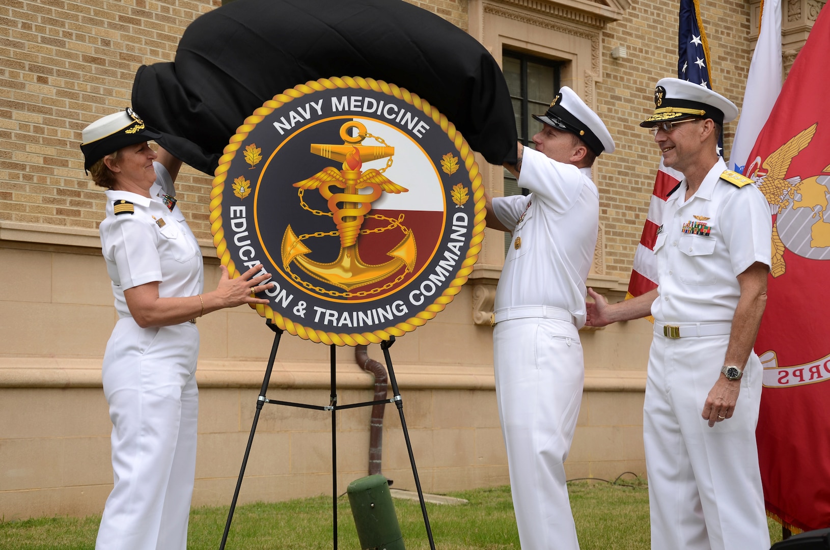 (From left) Capt. Gail Hathaway, commander Navy Medicine Education and Training Command; Command Master Chief James “Rusty” Perry, NMETC command master chief; and Navy deputy surgeon general Rear Adm. Michael H. Mittelman unveil NMETC’s new logo during the headquarters opening and ribbon-cutting ceremony at Joint Base San Antonio-Fort Sam Houston Sept. 28. 
Photo by L.A. Shively
