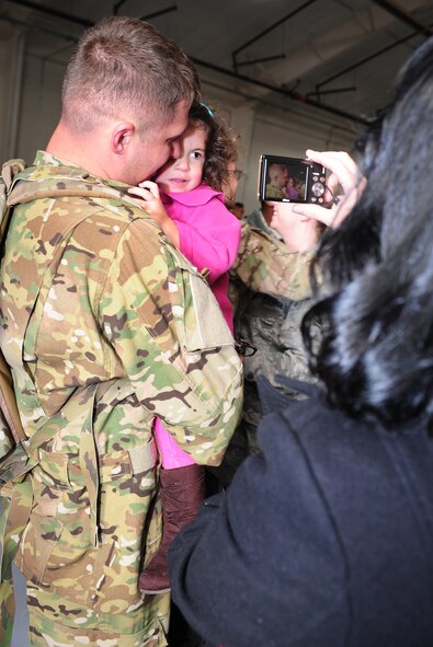 A service member gets his picture taken by a family member after reuniting with his daughter during Operation Homecoming at Cannon Air Force Base, N.M., Oct. 4, 2012. Operation Homecoming is a monthly event held to welcome Air Commandos back from worldwide deployments and reunite them with family and friends. (U.S. Air Force photo/Airman 1st Class Ericka Engblom)