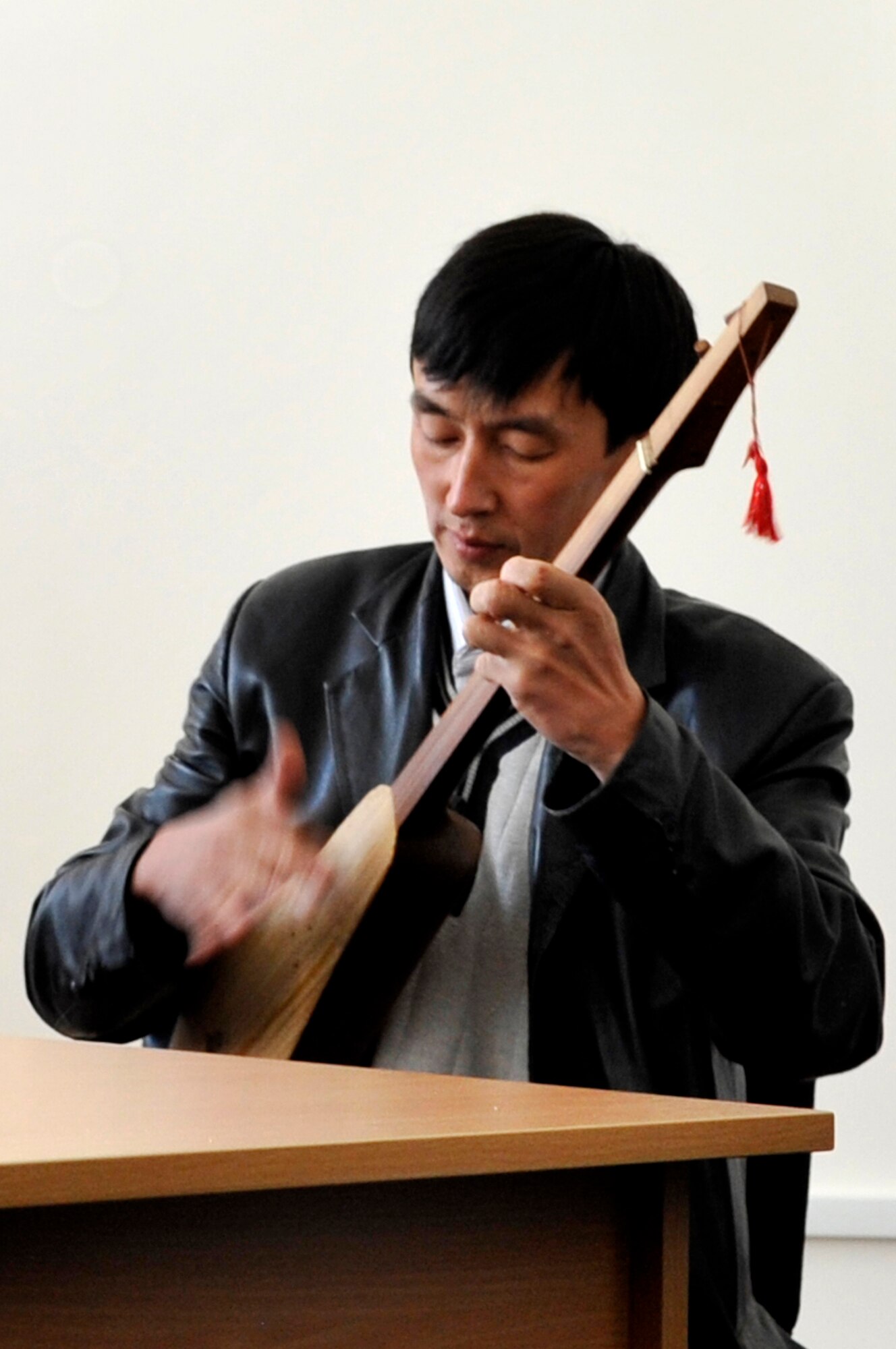 Janar Abdrazakov plays a Kyrgyz traditional guitar called a Komuz for members of the U.S. Air Forces Central Band "Top Flight" during a visit to the American Corner Sept. 27, 2012 in Naryn Province, Kyrgyzstan. Abdrazakov is a local music teacher in Naryn and was a guest for a music exchange with the members of the AFCENT band. The members of Top Flight were on a four-day U.S. Embassy led tour in the Naryn Province where they played for various audiences and conducted music exchanges with local students and staff. (U.S. Air Force photo/Master Sgt. Jason Vaught)