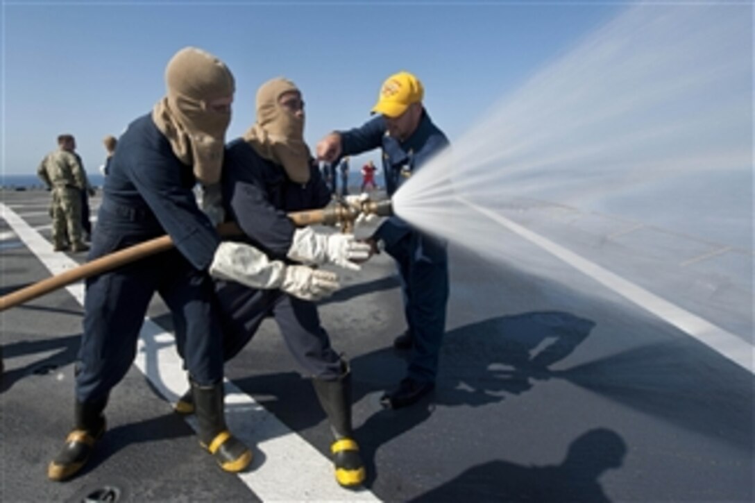 Chief Petty Officer Jeremiah Miller, right, instructs two sailors on the proper technique of using a fire hose during fire fighting training aboard the amphibious dock-landing ship USS Fort McHenry (LSD 43) as the ship operates in the Mediterranean Sea on Sept. 27, 2012.  