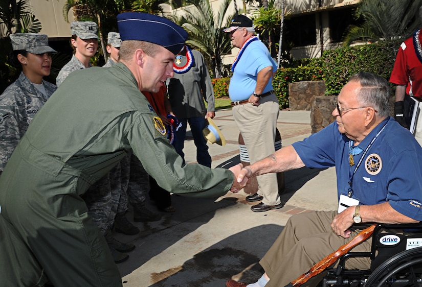 A  pilot shakes hands with a man in a wheelchair.
