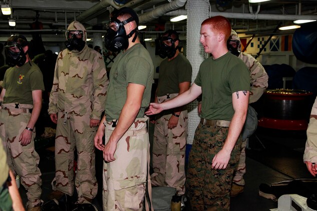 Lance Cpl. James R. Kerr, Chemical, Biological, Radiological and Nuclear Defense specialist, CBRN Platoon, 15th Marine Expeditionary Unit, demonstrates the proper removal of mission oriented protective posture gear to Marines from Weapons Company, Battalion Landing Team 3/5, 15th MEU, during a class on CBRN defense aboard the USS Peleliu, Oct. 4. The 15th MEU?s CBRN Defense Platoon is spending an entire month preparing the 2,400 servicemembers that make up the MEU on how to properly operate in contaminated environments. The 15th MEU is currently embarked as part of the Peleliu Amphibious Ready Group, while they serve as the nation's rapid-response sea-based Marine Air Ground Task Force for Western Pacific Deployment 12-02. Kerr, 19, is from Boston.