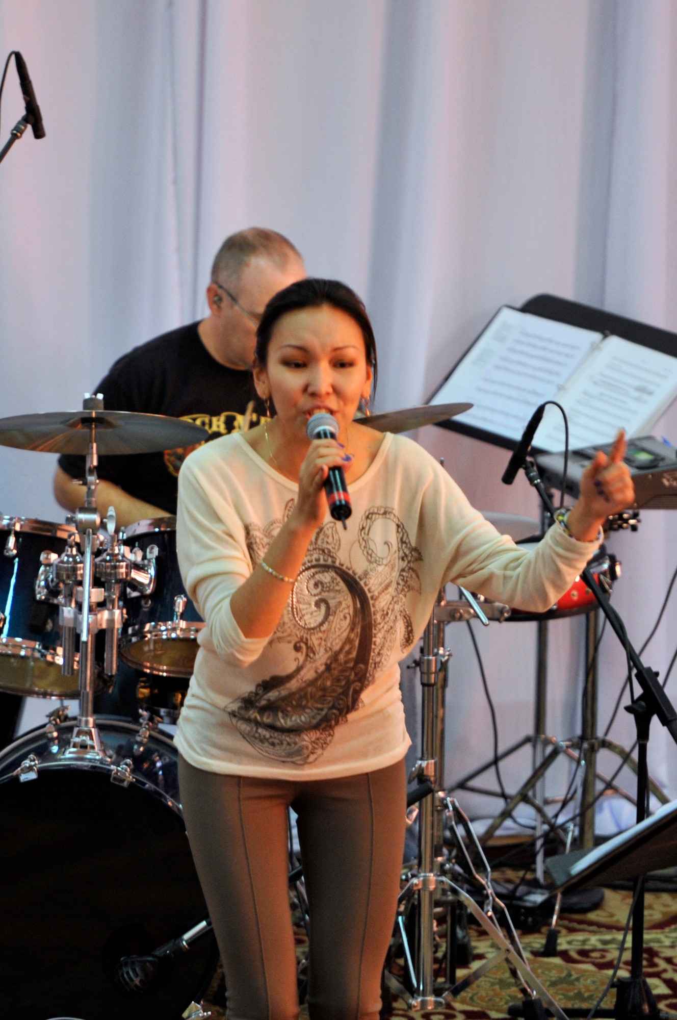 Aliman Temirbek sings with the band, "Top Flight" during a U.S. Air Forces Central band performance Sept. 27, 2012 at the House of Youth, Naryn Province, Kyrgyzstan. Temirbek, who is a Transit Center at Manas media relations specialist and a native of Bishkek, has joined four other AFCENT bands during their travels throughout the Kyrgyz Republic. The band performed for more than 800 Kyrgyz residents in Naryn while on a four-day U.S. Embassy led tour of the region. (U.S. Air Force photo/Master Sgt. Jason Vaught)