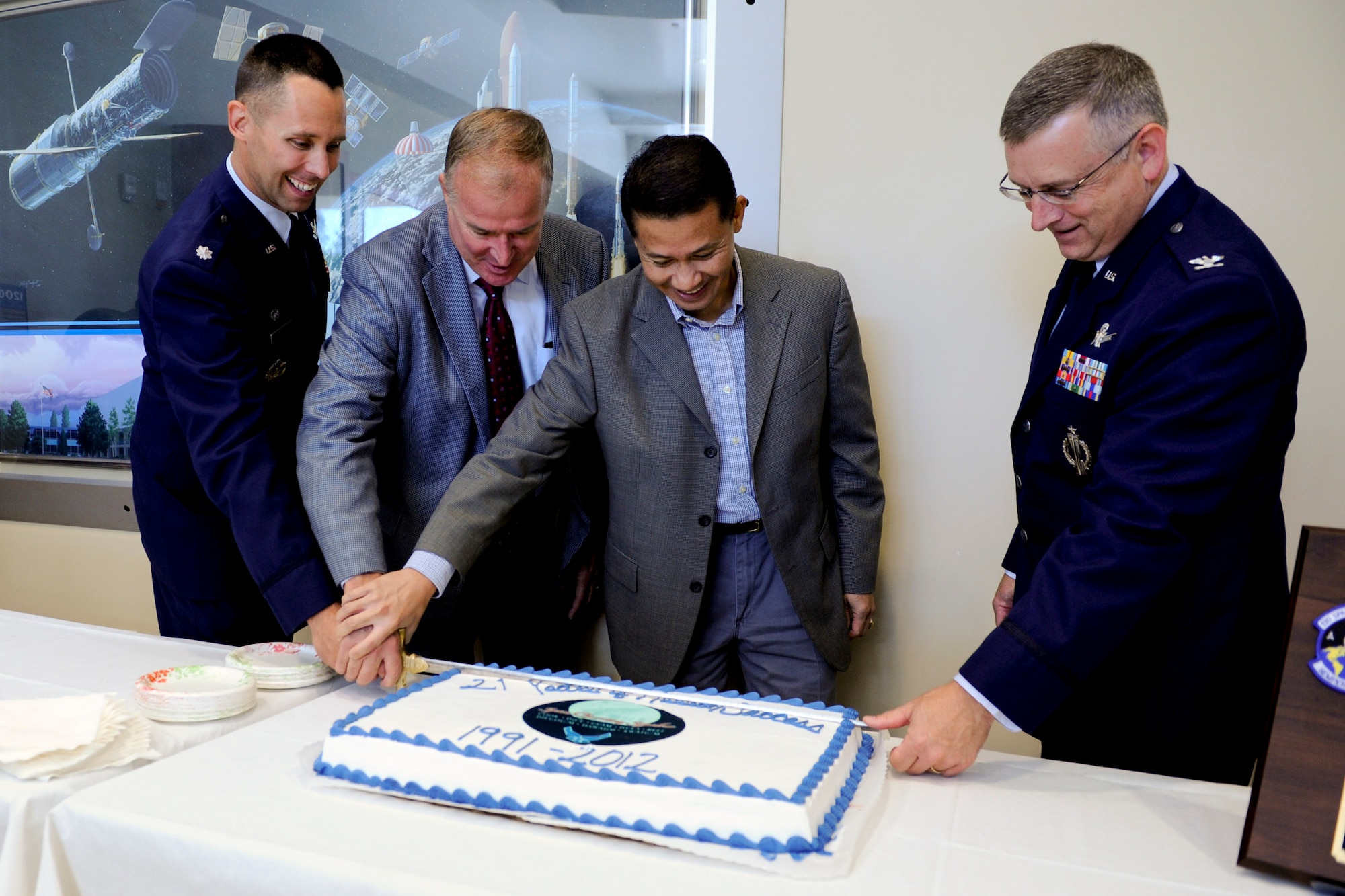 VANDENBERG AIR FORCE BASE, Calif. -- The current and former commanders of the 21st Space Operations Squadron but a birthday cake during a birthday celebration for the squadron here, Friday, Oct. 5, 2012. Active since 1991, the 21 SOPS handles the day-to-day operation and maintenance of the Air Force Satellite Control Network as well as ground antennas and monitoring stations. (U.S. Air Force photo/Staff Sgt. Levi Riendeau)
