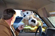 Sparky the Fire Dog hands a Fire Safety brochure to Eric Damgaard, 452nd Communications Squadron, as Damgaard enters the main gate during Fire Prevention week 2011. This year, Nov. 7 though 13 has been set aside to promote fire safety. (U.S. Air Force photo by Linda Welz)