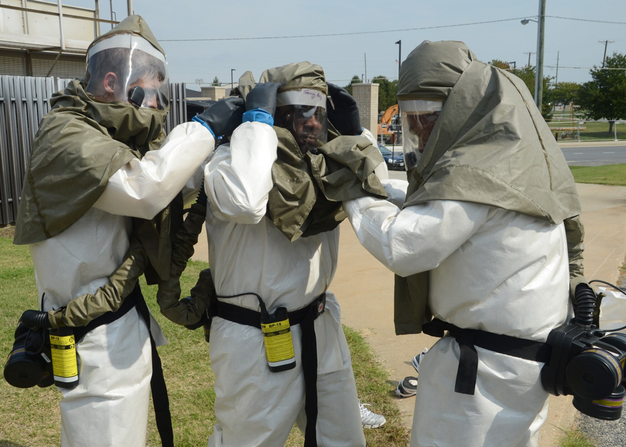 Master Sgt. Michael Arms, center, dons his decontamination mask while Airman 1st Class Alexander Delfs, left, and Tech. Sgt. Aisha Toston help Arms adjust his gear Sept. 27, 2012, at the 436th Medical Group Clinic on Dover Air Force Base, Del. Members of the 436th MDG patient decontamination team received hands-on training on In-Place Patient Decontamination procedures. The IPPD is used at the medical treatment facility to decontaminate casualties and responders. (U.S. Air Force photo by Tech. Sgt. Chuck Walker)