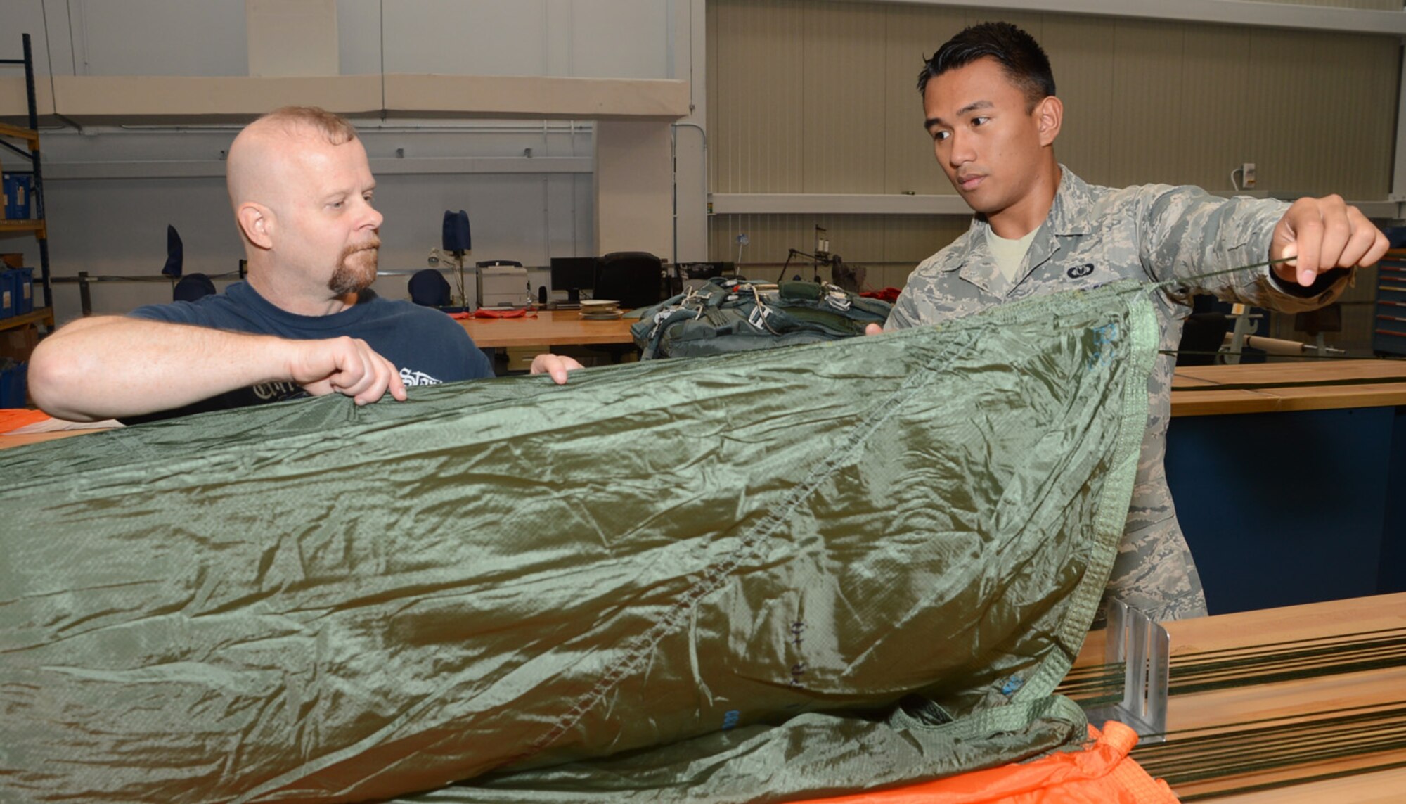 Dave Compton, left, instructs Airman 1st Class Poler Oliveros on how to properly pack a parachute Oct. 5, 2012, at the Aircrew Flight Equipment building on Dover Air Force Base, Del. Compton was named the Air Force’s 2011 Outstanding Aircrew Flight Equipment Civilian Category II of the Year last week. (U.S. Air Force photo by Tech. Sgt. Chuck Walker)