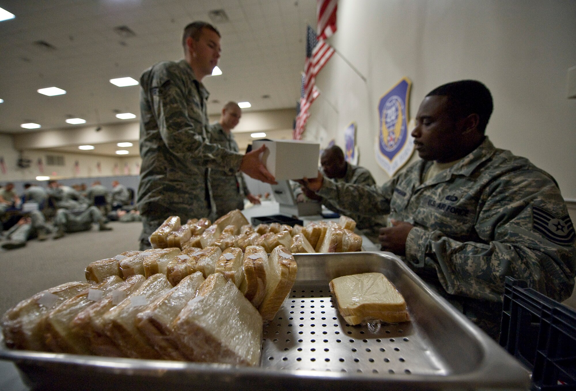 Airmen from the 96th Bomb Squadron receive boxed meals while waiting to board their flight to Guam for a deployment from Barksdale Air Force Base, La., Oct. 1. The Airmen can't leave the holding area once they are cleared to board the flight, so food was provided on-location. (U.S. Air Force photo/Staff Sgt. Chad Warren)(RELEASED)