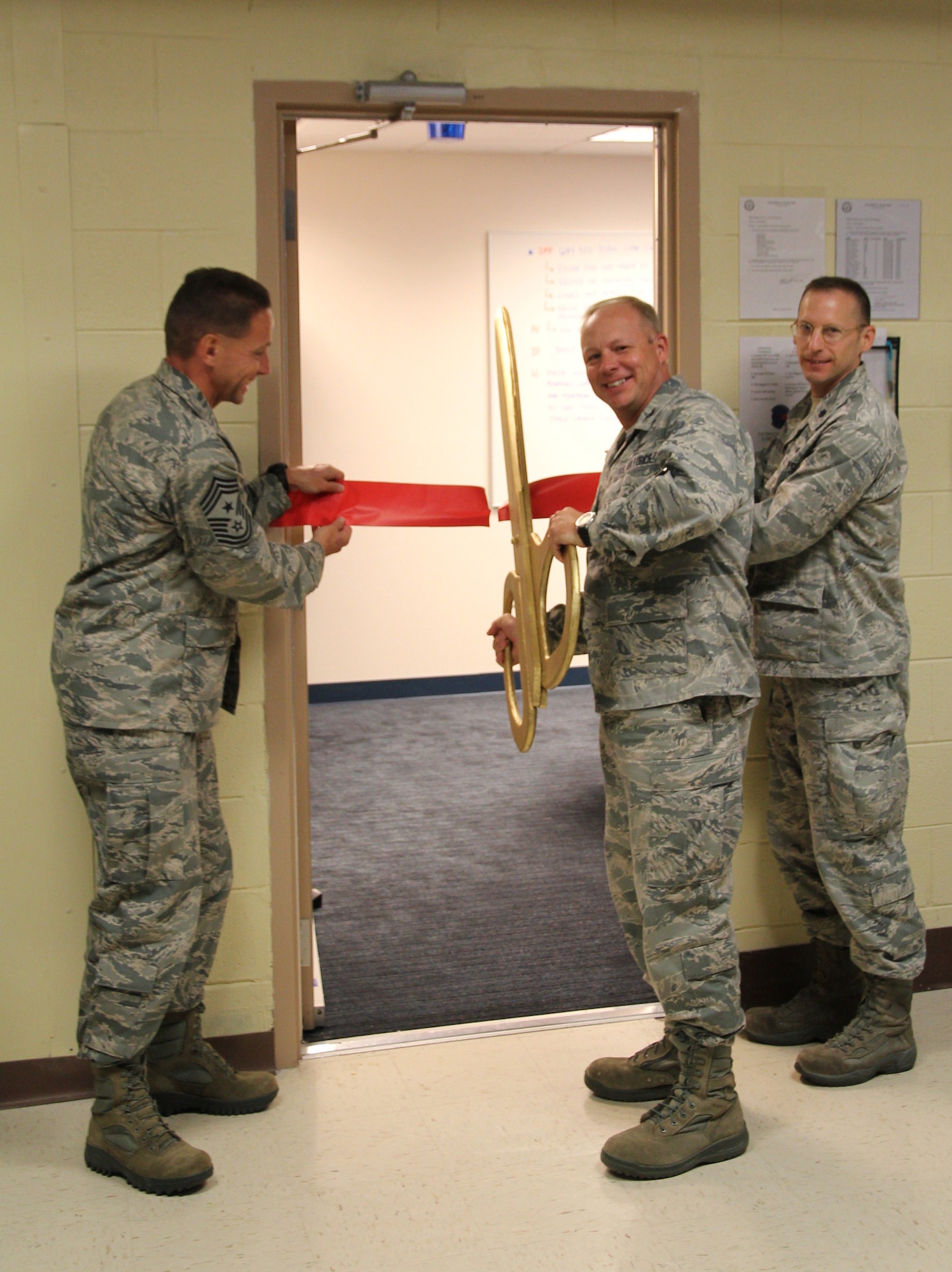 (Left to right) Chief Master Sgt Richard Redman, 21st Space Wing command chief, Col. Chris Crawford, 21st SW commander, and Lt. Col. Mitch Katosic, 20th Space Control Squadron commander, cut the ribbon on a new 20th SPCS sensitive compartmented information facility recently. The new SCIF will allow the 20th Space Control Squadron to process top secret information to enhance tactical mission planning in support of their space situational awareness mission. (U.S. Air Force photo)
