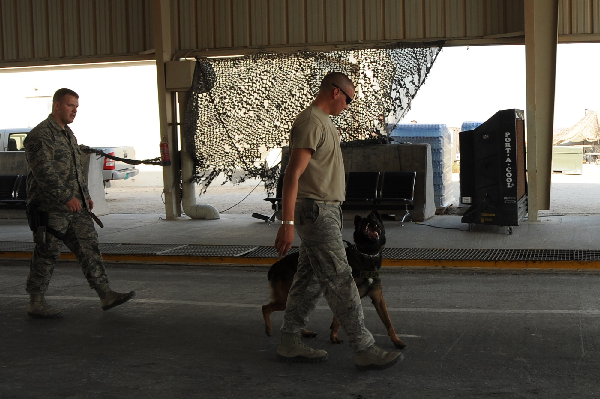 U.S. Air Force military working dog, Toki, walks closely to the apprehended member, Staff Sgt. Travis Beatty, while SSgt. Jeremy Hayes walks behind them in Southwest Asia, October 1, 2012. Military working dogs are taught to escort members giving the military working dog handler an opportunity to have distance away from the member who was apprehended. (U.S. Air Force photo/Staff Sgt. Sheila deVera)