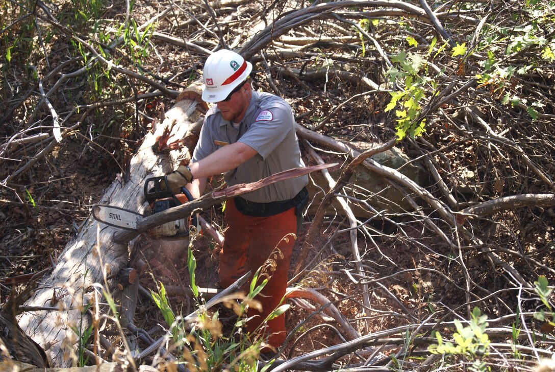 Park ranger Nick Wilson uses a chainsaw to cut a tree that fell onto the Younger Bend hiking trail at Eufaula Lake during the clean-up event. 