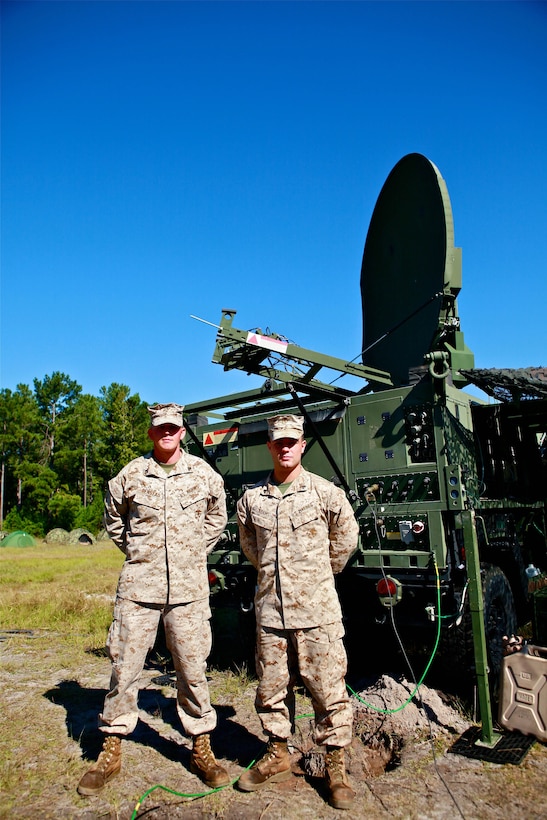 Cpl. Philip J. Denstad (left), a satellite technician and Cpl. Thomas Adams (right), a satellite communications operator and maintenance specialist, both with Alpha Company, 8th Communications Battalion, II Marine Expeditionary Force Headquarters Group, stand in front of the ANTCS-156C Phoenix Terminal during 8th Comm. Bn.'s field exercise aboard Marine Corps Base Camp Lejeune, Sept. 25. The Phoenix Terminal pulls data from a satellite to provide internet, phone and data capabilities to Marines in the field and deployed.