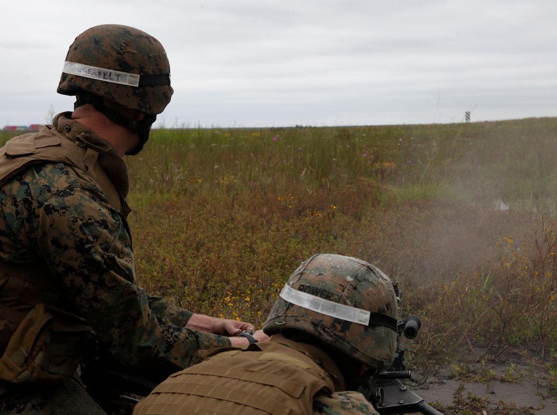 Sgt. Joshua M. Bower, an instructor with Infantry Training Battalion, School of Infantry – East, sits behind an M240B waiting to fire as Sgt. Dane K. Summerfelt, an instructor with ITB, SOI – East, feeds rounds and relays adjustments during an instructor-only class on firing from the defilade aboard Marine Corps Base Camp Lejeune Sept. 24. Learning to shoot from the defilade teaches Marines how to send rounds down range and impact targets they cannot see from the firing position using a direct-fire M240B machine gun. 