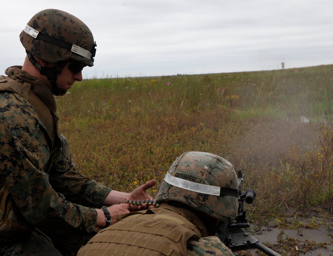 Sgt. Joshua M. Bower, an instructor with Infantry Training Battalion, School of Infantry – East, sits behind an M240B waiting to fire as Sgt. Dane K. Summerfelt, an instructor with ITB, SOI – East, feeds rounds and relays adjustments during an instructor-only class on firing from the defilade aboard Marine Corps Base Camp Lejeune Sept. 24. Learning to shoot from the defilade teaches Marines how to send rounds down range and impact targets they cannot see from the firing position using a direct-fire M240B machine gun. 