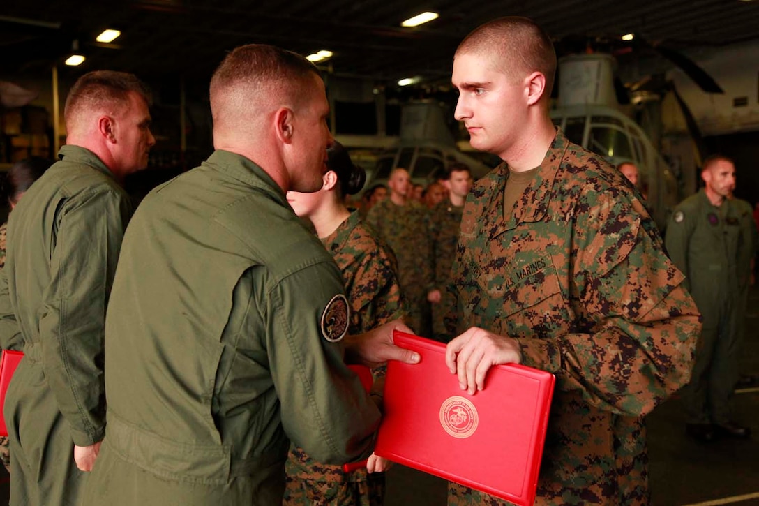 Lance Cpl. Dennis P. Dewey, avionics electrician, Marine Medium Helicopter Squadron 364 (Rein.), 15th Marine Expeditionary Unit, receives a Certificate of Commendation from Lt. Col. Ned M. Biehl, the squadron’s commanding officer, for his efforts during the unit’s pre-deployment training, in the hangar bay of the USS Peleliu, Oct. 1. The 15th MEU is currently embarked as part of the Peleliu Amphibious Ready Group, while they serve as the nation's rapid-response sea-based Marine Air Ground Task Force for Western Pacific Deployment 12-02. Dewey, 20, is from Enumclaw, Wash.