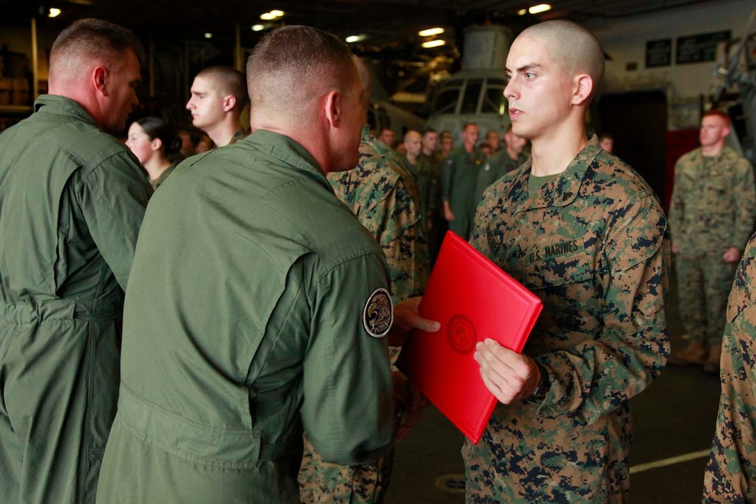 Corporal Alec J. Schreiber, intelligence analyst, Marine Medium Helicopter Squadron 364 (Rein.), 15th Marine Expeditionary Unit, receives a Certificate of Commendation from Lt. Col. Ned M. Biehl, the squadron’s commanding officer, for his efforts during the unit’s pre-deployment training, in the hangar bay of the USS Peleliu, Oct. 1. The 15th MEU is currently embarked as part of the Peleliu Amphibious Ready Group, while they serve as the nation's rapid-response sea-based Marine Air Ground Task Force for Western Pacific Deployment 12-02. Schreiber, 21, is from Oakley, Calif.