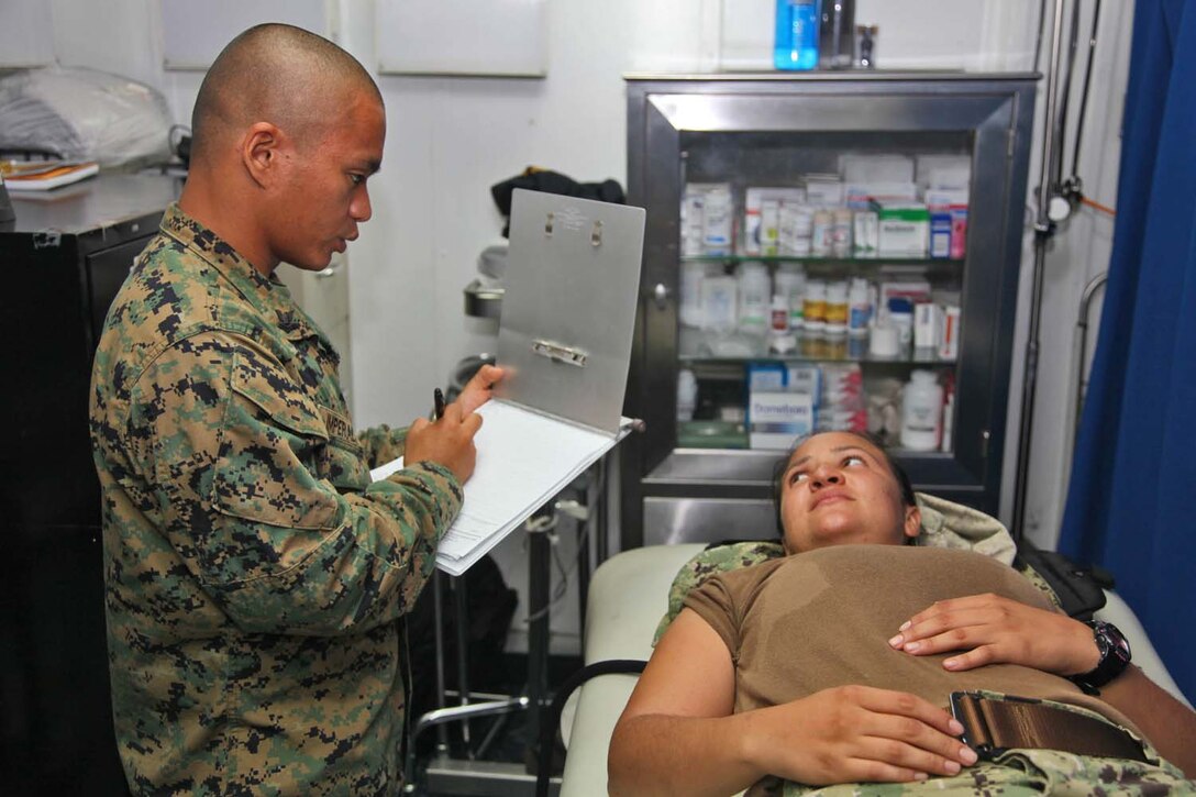 Petty Officer 2nd Class William B. Imperial, corpsman, Combat Logistics Battalion 15, 15th Marine Expeditionary Unit, evaluates Fireman Andrea Rivero, hull technician, Assault Craft Unit 5, during daily sick-call on board the USS Rushmore, Oct. 3. Although it’s much smaller than the Peleliu Amphibious Ready Group’s flag ship, the USS Peleliu, the medical and dental departments aboard the Rushmore are capable of preventing and treating illnesses and minor injuries, cleaning teeth and removing cavities, training and educating Marines and sailors and preparing for the rapid treatment of combat casualties. Imperial, 25, is from Manila, Philippines and Rivero, 24, is from Beaufort, Ga.