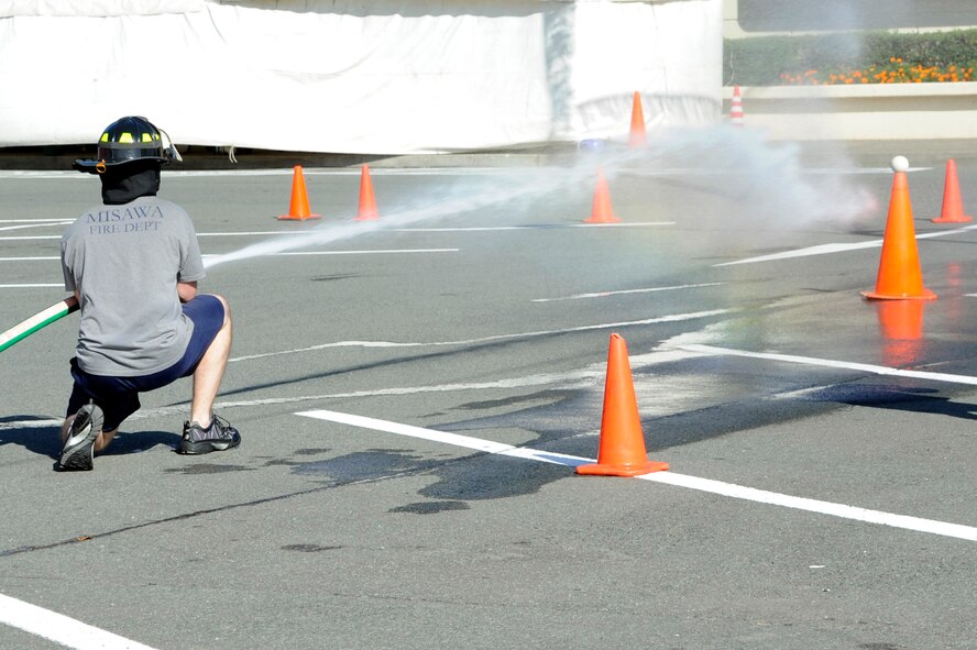 U.S. Air Force Airman 1st Class Bradley Kramer, 35th Civil Engineer Squadron Team B member, tries to knock a ball off a cone during the hose pull discharge event part of the firefighter combat challenge relay, at Misawa Air Base, Japan, Oct. 7, 2012. Four teams from Misawa Air Base, Misawa City and Towada City competed against each other with the fastest time going to Misawa Air Base Team B at one minute, 22 seconds. (U.S. Air Force photo/Tech. Sgt. Marie Brown)