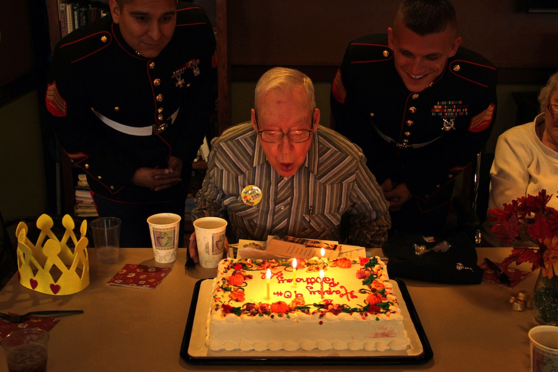 Sgts. Julio Gonzalez and Adam Kruse watch Alson Bondy celebrate his 90th birthday at Inver Glen Senior Living on Oct. 5. Bondy served in the Marine Corps as a corsair pilot during World War II. The two recruiters out of the Woodbury, Minn., office stopped by the event after being contacted by one of the residents who knew about Bondy's service.