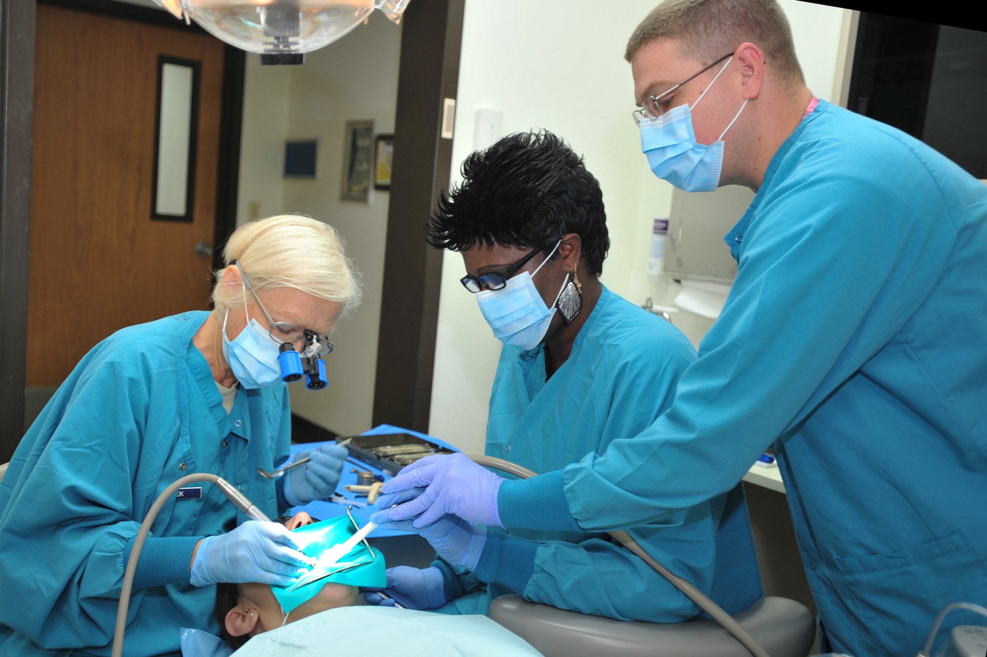 Staff Sgt. William Lodge, (right) 51st Dental Squadron technician, and Lt. Col. Miroslawa Dudek, (left) 51st DS dentist, guide Annmarie Gregory, a Red Cross volunteer dental assistant, through a routine dental procedure on Osan Air Base, Republic of Korea, Oct. 4, 2012. Red Cross dental volunteers train beneath dental staff members for six months and acquire 1,000 volunteer hours for their certifications. (U.S. Air Force photo/Airman 1st Class Alexis Siekert)