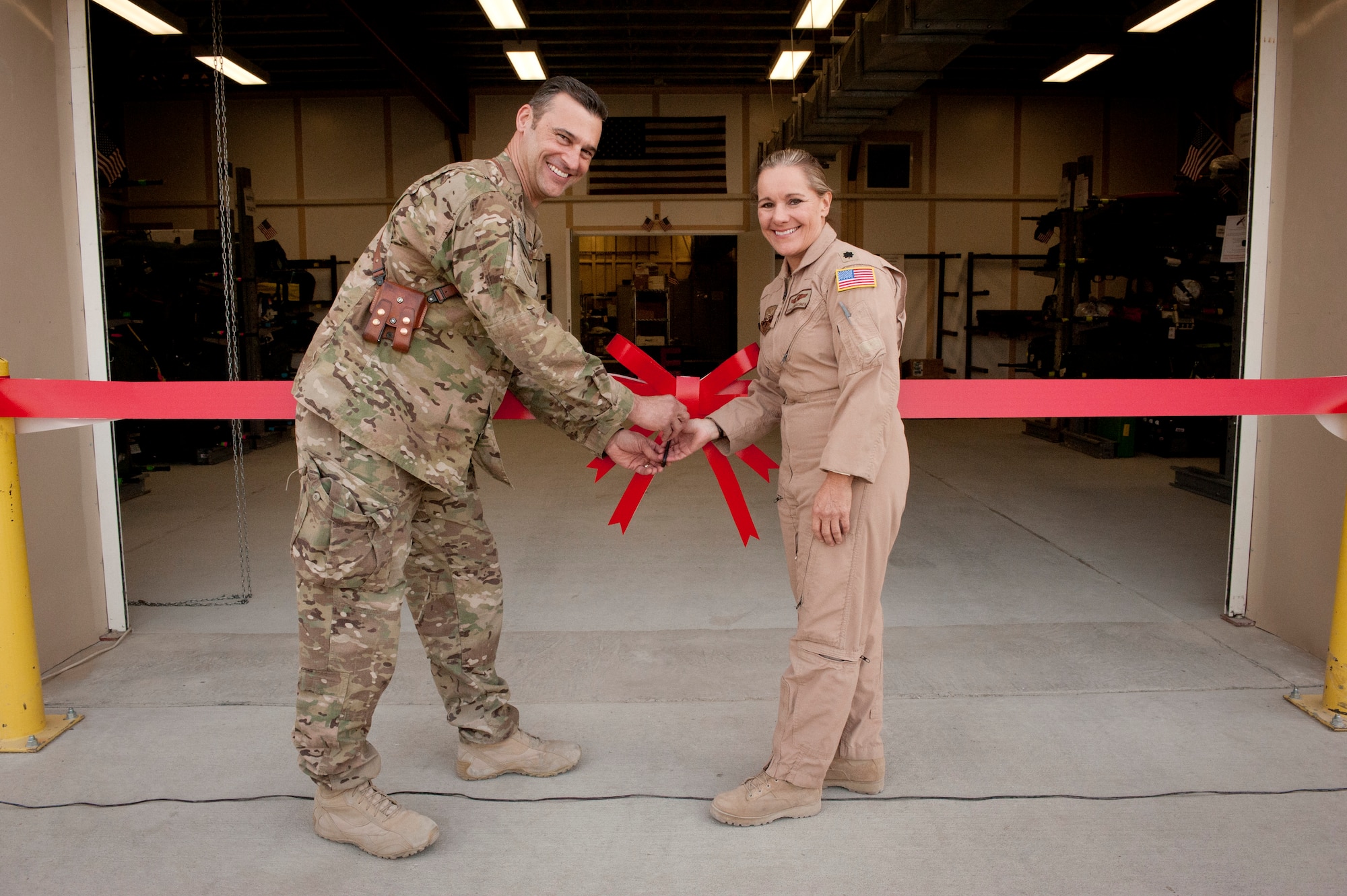Brig. Gen. Joseph Guastella, 455th Air Expeditionary Wing Commander, and Lt. Col. Carla Marcinek, 455th Expeditionary Aeromedical Evacuation Squadron Commander, prepare to cut the ribbon to open the new 455 EAES building. The new facility will enable the unit to provide better patient care to wounded servicemembers. (U.S. Air Force photo/SSgt Neal Uranga)