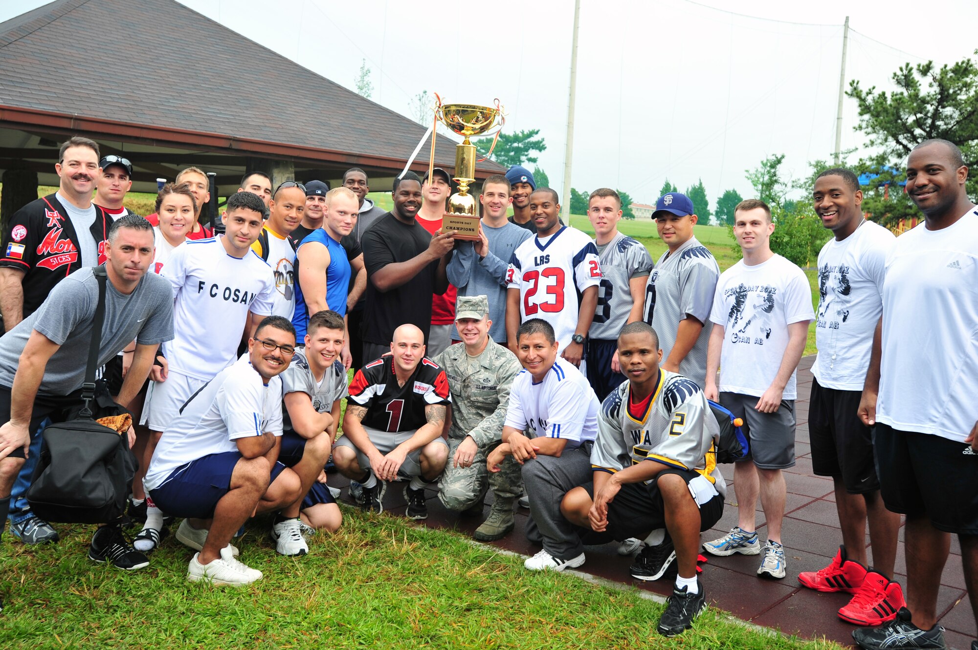 Team Osan members gather around their first place trophy following the 2012 Sports Day competition at Osan Air Base, Republic of Korea, Sept. 28, 2012. Participants from across the peninsula traveled from Kunsan and Daegu air bases to compete in a day full of sporting events at Osan to include football, softball, dodge ball, volleyball and bowling. (U.S. Air Force photo/Airman 1st Class Alexis Siekert)
