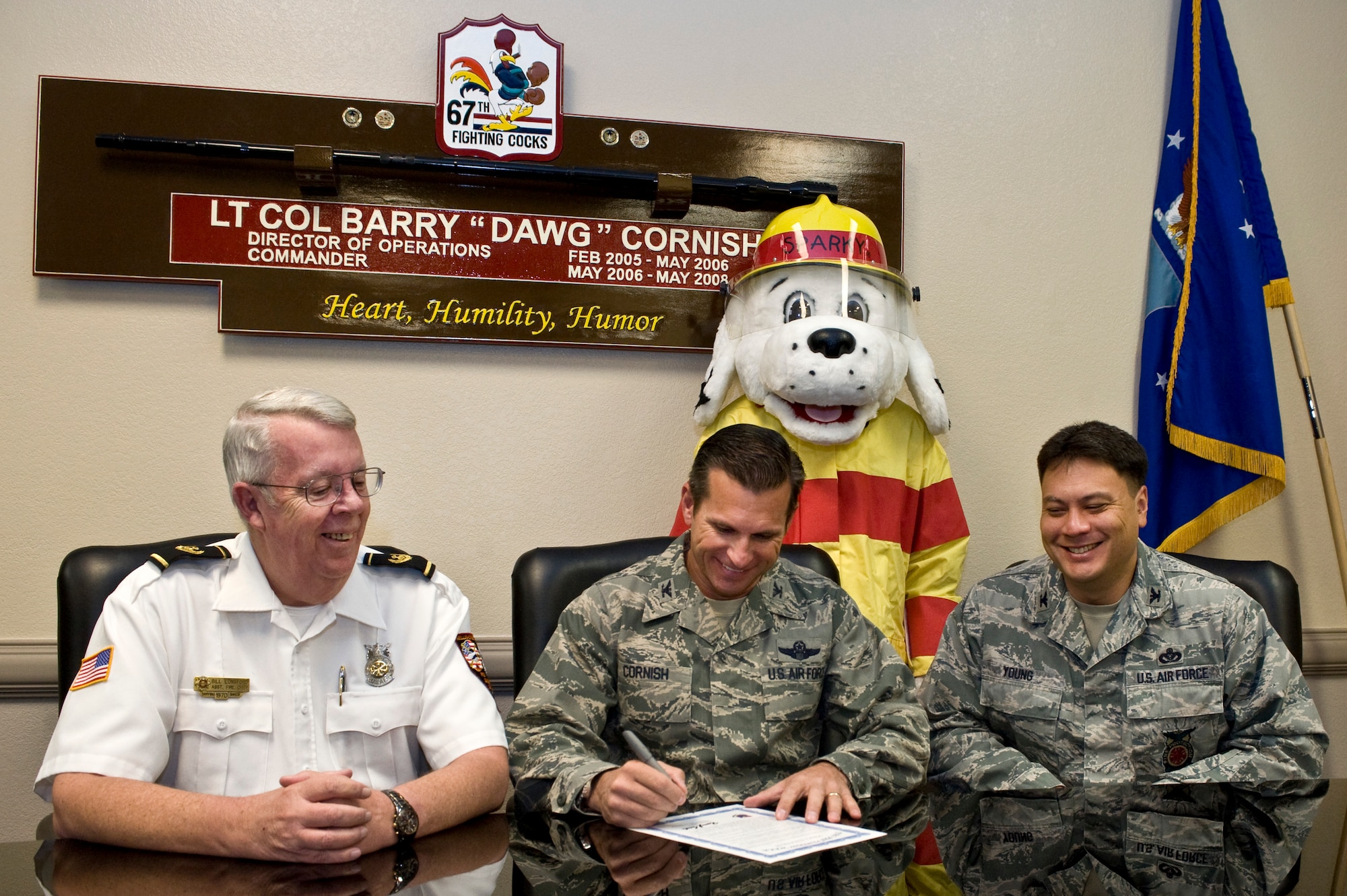 Col. Barry Cornish, 99th Air Base Wing commander, signs the 2012 Fire Prevention Week proclamation while Bill Lonsford, 99th Civil Engineer Squadron assistant fire chief, Sparky, the fire dog, and Col. Aaron Young, 99th Civil Engineer Squadron commander, watch, Oct. 9, 2012, at Nellis Air Force Base, Nev. Nellis, Creech and the Nevada Test and Training Range will celebrate National Fire Prevention Week Oct. 7-13, 2012. During National Fire Prevention Week attention is focused on promoting fire safety and prevention. (U.S. Air Force photo by Airman 1st Class Matthew Lancaster)