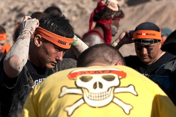 Senior Airman Howard Zumbrunnen, 757th Aircraft Maintenance Squadron crew chief, puts on the Tough Mudder headband after completing the Tough Mudder obstacle course at Spicer Ranch Oct. 6, 2012, in Beatty, Nev. Airmen of the 757th AMXS and all contenders receive a Tough Mudder headband after completion of the ten mile course. (U.S. Air Force photo by Staff Sgt. Christopher Hubenthal)