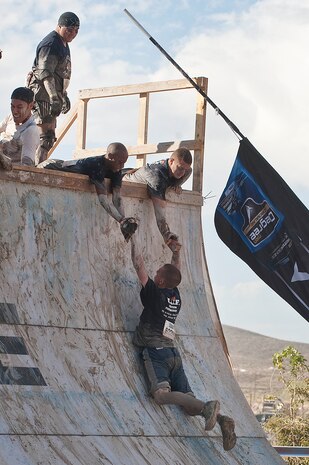 Senior Airman Michael Allen, and Senior Airman Gregory Schild, 757th Aircraft Maintenance Squadron crew chiefs, help Senior Airman Steven Tabaczynski, 757th AMXS crew chief, up an obstacle during the Tough Mudder obstacle course at Spicer Ranch Oct. 6, 2012, in Beatty, Nev. Tough Mudder supports the Wounded Warrior Project by utilizing proceeds towards providing combat stress recovery programs, adaptive sports programs, benefits counseling, and employment services to military members returning from the battlefield. (U.S. Air Force photo by Staff Sgt. Christopher Hubenthal)
