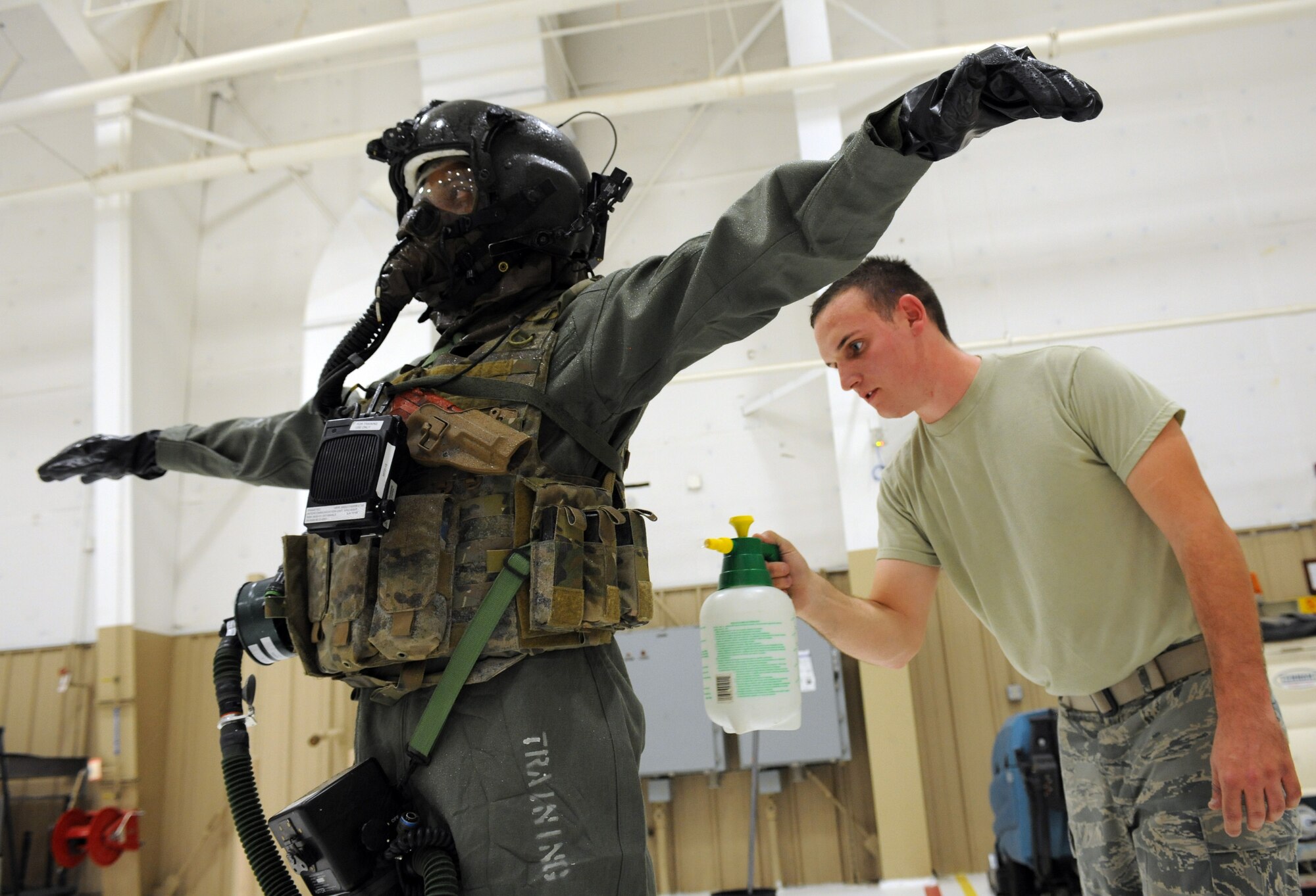 U.S. Air Force Senior Airman Jason, 1st Operations Support Squadron, Joint Base Langley-Eustis, Va., sprays down Staff Sgt. Kendrick Walker, 7th OSS, Dyess Air Force Base, Texas, during aircrew decontamination training on Davis-Monthan AFB, Ariz., Sept. 21, 2012. The training took aircrew flight equipment technicians through each stage of mitigation on several aircrew flight suits. The basic premise of mitigation remained the same, but AFE technicians had to adapt the training to the different equipment. (U.S. Air Force photo by Airman 1st Class Timothy Moore/Released)