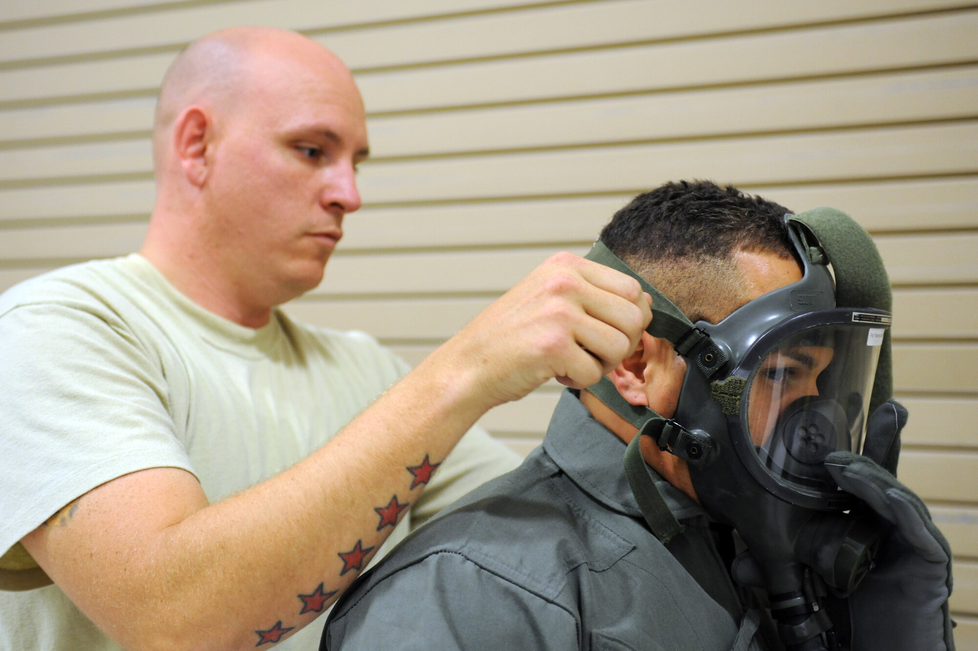U.S. Air Force Staff Sgt. Michael Bryant, 563rd Operations Support Squadron, helps Staff Sgt. Jonathan Rivera, 4th OSS, Seymour Johnson Air Force Base, N.C., tighten a gas mask before the hands-on aircrew decontamination training on Davis-Monthan AFB, Ariz., Sept. 21, 2012. Airmen from several bases under Air Combat Command came to D-M to learn the proper procedures to mitigate possible contamination on aircrews. (U.S. Air Force photo by Airman 1st Class Timothy Moore/Released)