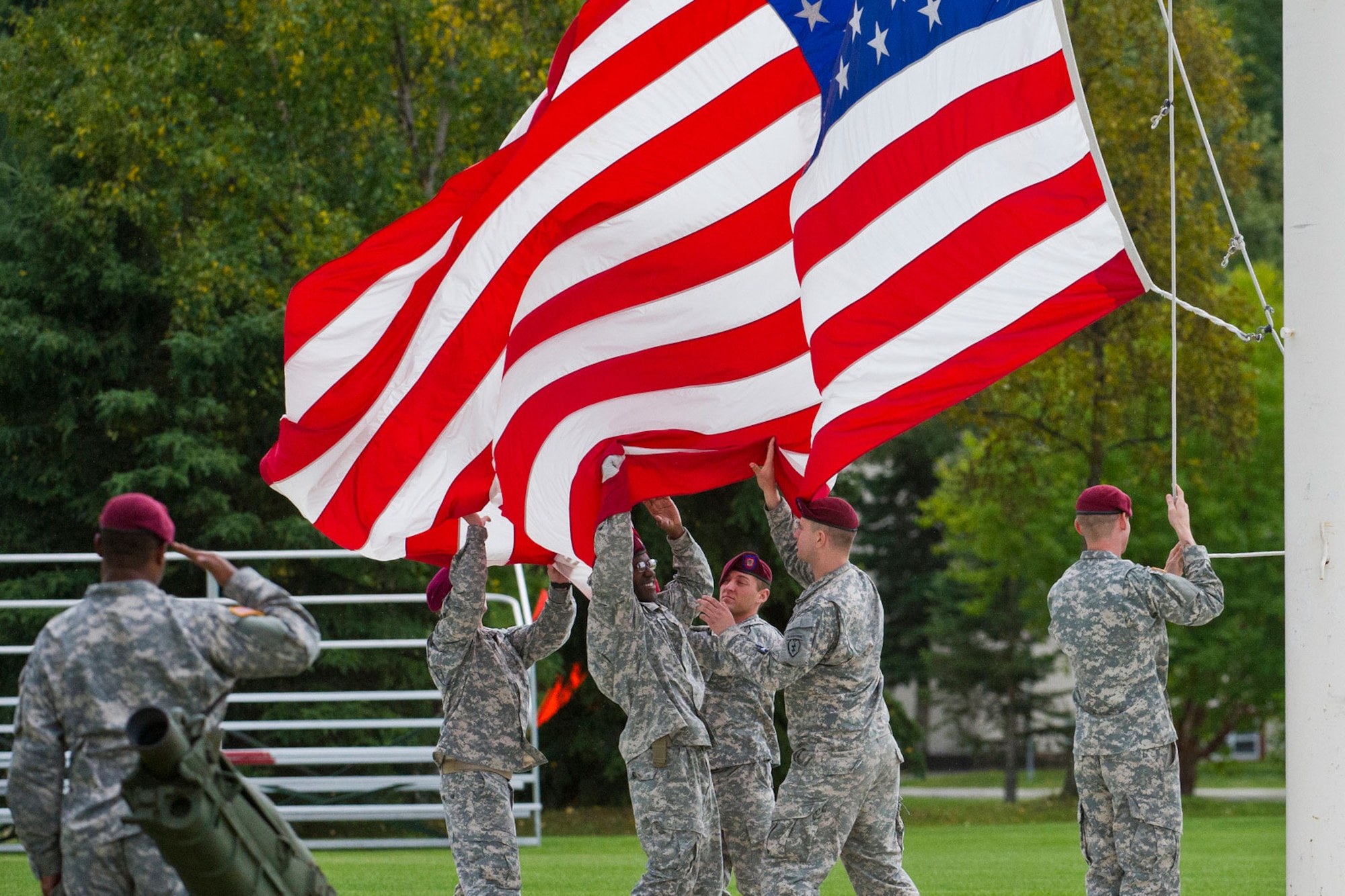 Specialist Reese Dawson, assigned to 1st Battalion (Airborne) 501st Infantry Regiment, of Philadelphia, Pa., left, renders honors to the colors during Retreat as fellow paratroopers catch the colors as it is lowered on Pershing Field at U.S. Army Alaska Headquarters, recently. Retreat, or To The Colors, signifies the end to the official duty day on U.S. military installations. (U.S. Air Force photo/Justin Connaher)