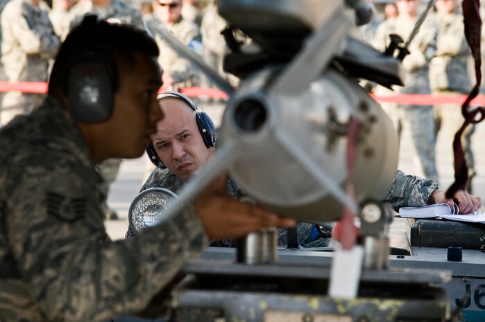 U.S. Air Force Senior Airman David Murray, Aircraft Maintenance Squadron weapons load crew member, watches Staff Sgt. Treston Kaneao, 57th Aircraft Maintenance Squadron weapons load crew member, lock the Mk-82 general purpose bomb onto an F-16 Fighting Falcon during a load crew competition Oct. 5, 2012, at Nellis Air Force Base, Nev. Competition teams must follow every step and take their time, ensuring timeliness and accuracy in weapons loading. (U.S. Air Force photo by Senior Airman Daniel Hughes)