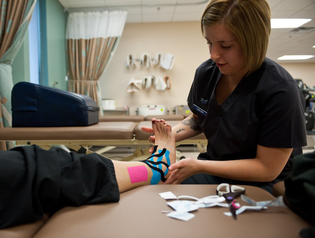Senior Airman Haylley Carlson, 28th Medical Operations Squadron physical therapy technician, applies kinesio tape on a patient’s ankle to reduce swelling and increase blood flow to the area at Ellsworth Air Force Base, S.D., Oct. 4, 2012. The different colored tapes signify whether the injured area is being treated with hot or cold treatment. (U.S. Air Force photo by Airman 1st Class Alystria Maurer/Released)