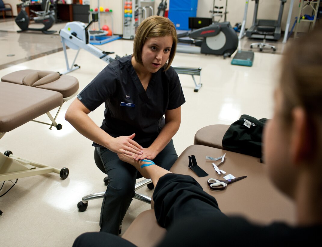 Senior Airman Haylley Carlson, 28th Medical Operations Squadron physical therapy technician, explains kinesio taping procedures to a patient at Ellsworth Air Force Base, S.D., Oct. 4, 2012. Kinesio taping is a therapeutic taping method using uniquely designed elastic tape which can be used on a wide range of injuries. (U.S. Air Force photo by Airman 1st Class Alystria Maurer/Released)