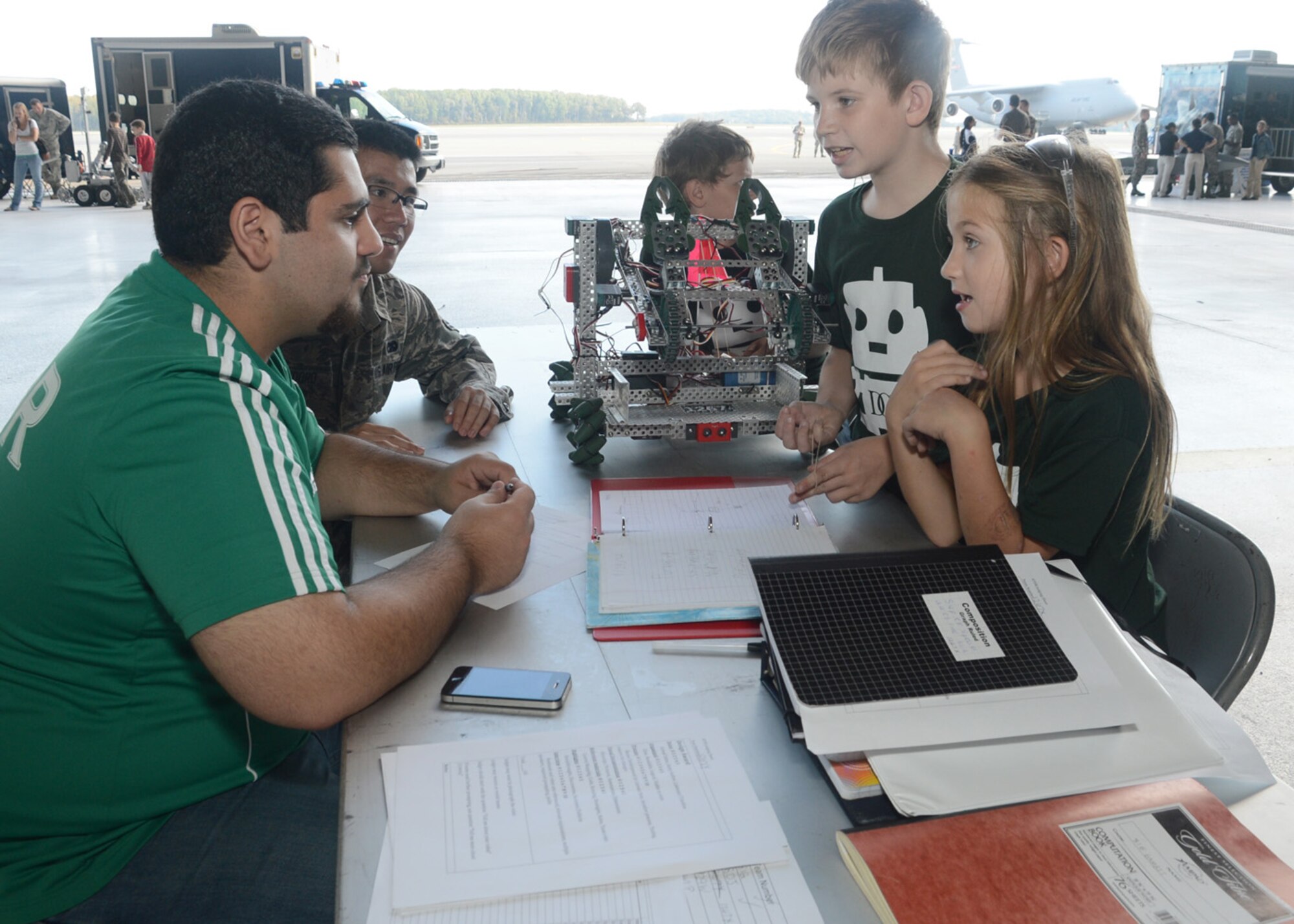 Judges Eli Canavati, from Drexelville, Pa. and Airman 1st Class Juanangelo Teodoro, of the 436th Aerial Port Squadron, listen to the brother and sister team of Peter of Erika Crane, of Paoli, Pa., as they explain the workings of their robot Oct. 6, 2012, at Hangar 706 on Dover Air Force Base, Del. Part of the overall judging of the competiton was the notebook portion, or design, where competitors told judges about the design of their robot and how it worked. (U.S. Air Force photo by Tech. Sgt. Chuck Walker)