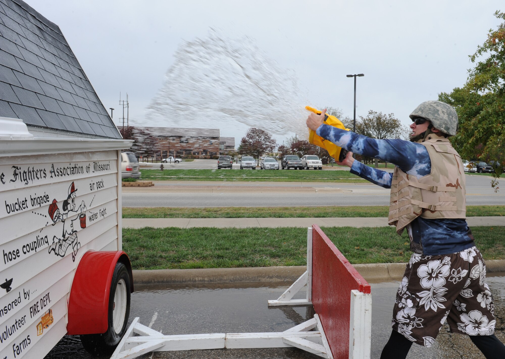WHITEMAN AIR FORCE BASE, Mo. -- A member of the Wolfpack Fire Muster team throws water on a roof during the Bucket Brigade challenge, Oct. 6. The object of the Bucket Brigade challenge is to throw water on a roof, as the water funnels down the gutter it goes into a barrel. The winner must fill up a barrel until it overflows in the fastest time. (U.S. Air Force photo/Airman 1st Class Bryan Crane) (Released)