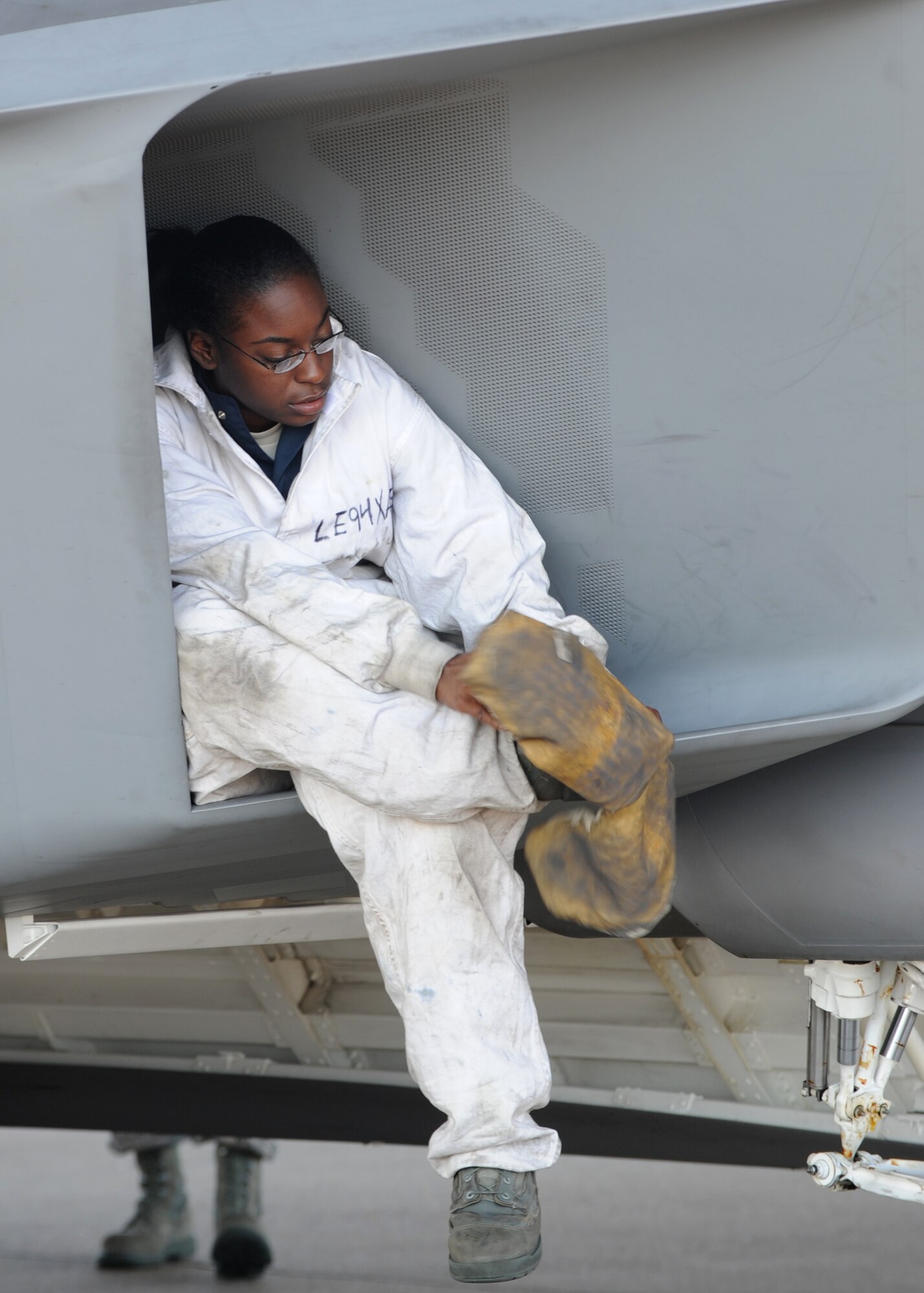 U.S. Air Force Senior Airman Kimara Duncan, 94th Aircraft Maintenance Unit tactile aircraft maintainer, slides booties over her boots during routine maintenance on an F-22 Raptor at Langley Air Force Base, Va., Sept. 25, 2012. Duncan, like most crew chiefs, often works 10- to 12-hour shifts. (U.S. Air Force photo by Senior Airman Racheal Watson/Released)