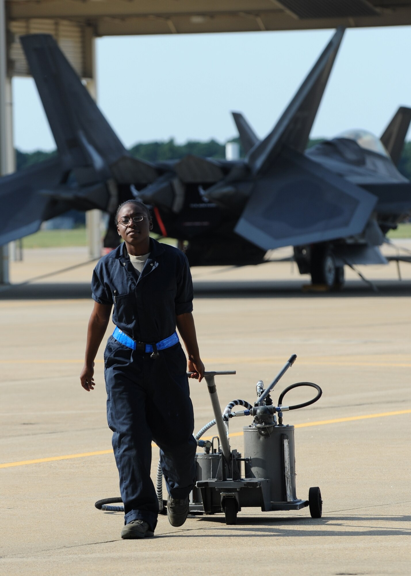 U.S. Air Force Senior Airman Kimara Duncan, 94th Aircraft Maintenance Unit tactile aircraft maintainer, pulls an oil cart across the flight line during routine maintenance on an F-22 Raptor at Langley Air Force Base, Va., Sept. 25, 2012.  As a young Airman just starting technical training, Duncan was excited to learn she would be trained to work on the most technologically advanced fighter jet in the world. (U.S. Air Force photo by Senior Airman Racheal Watson/Released)