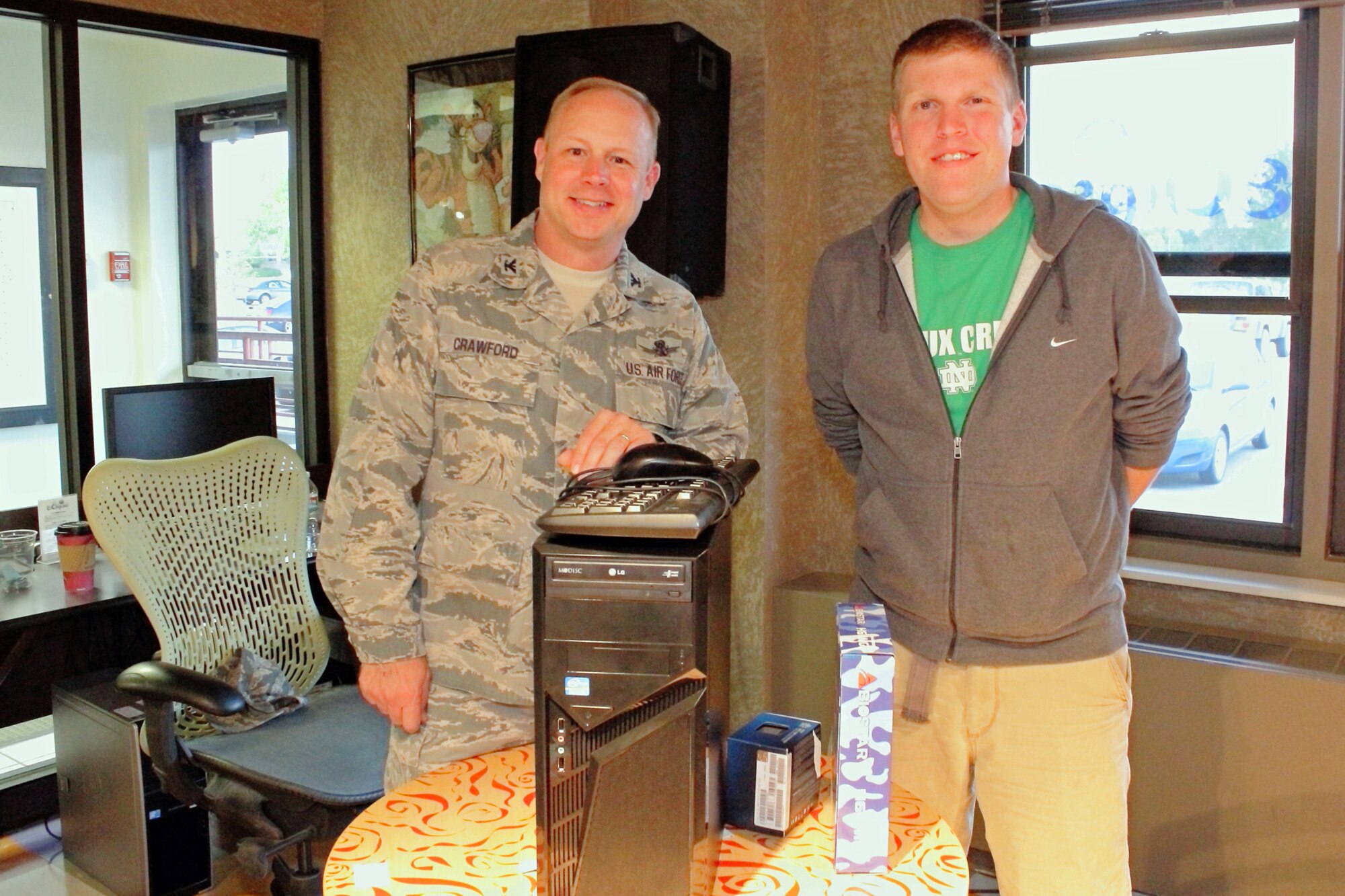 Col. Chris Crawford, 21st Space Wing commander, presents a custom built gaming computer to Airman 1st Class Andrew Revier at the reopening of the Eclipse cyber café Sept. 28. The café, sponsored by the chapel, provides free coffee and a place for dorm residents to socialize. (Courtesy photo/William Davis)