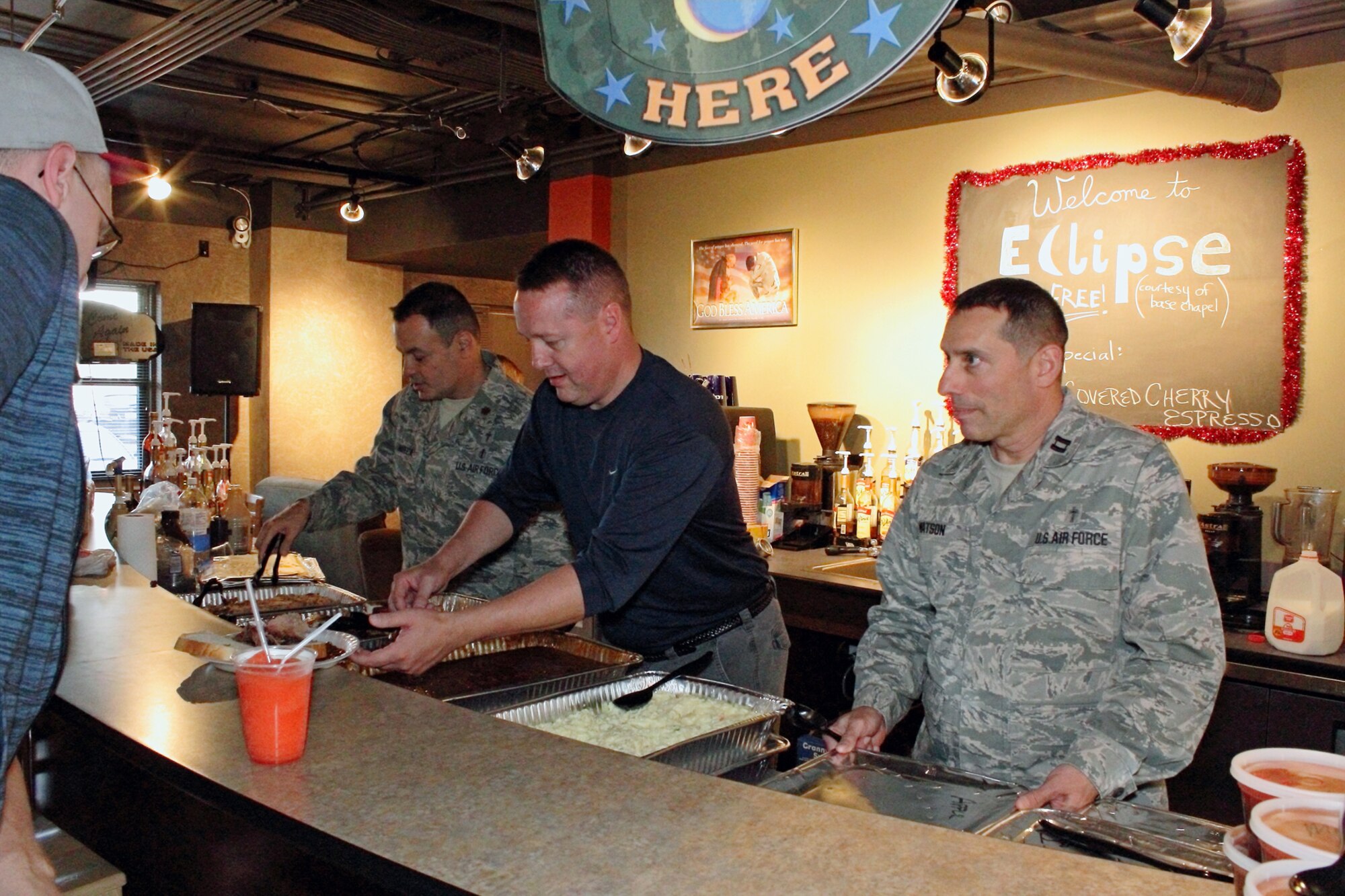 Chaplains (Maj.) Oscar Fonseca (left), (Capt.) Gary Willeford, and (Capt.) Joe Watson serve dinner to dorm residents Sept. 28. The dinner was part of the grand reopening of the Eclipse Cyber Café. The café, sponsored by the chapel, provides free coffee and a place for dorm residents to socialize. (Courtesy photo/William Davis)