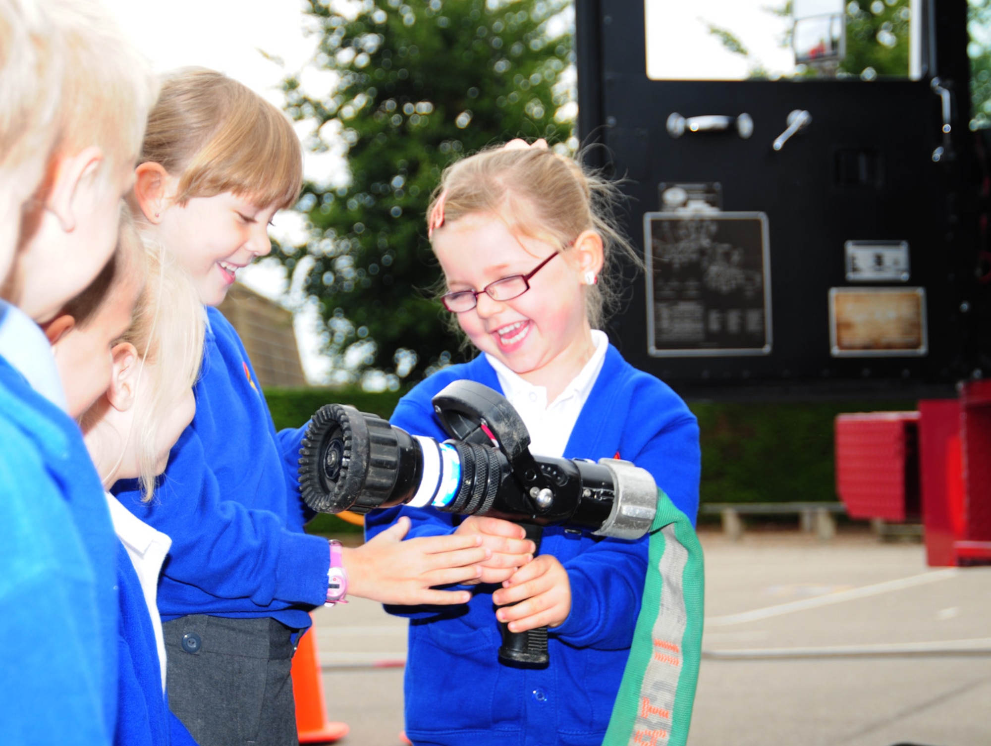 Children from St. Mary's Academy in Mildenhall, England, take a look at a fire hose on a fire truck from RAF Mildenhall Oct. 8, 2012. Firefighters, along with Sparky the Fire Dog, visited the children and brought their fire prevention trailer to teach children how to get out of the house in the event of a fire. (U.S. Air Force photo/Karen Abeyasekere)