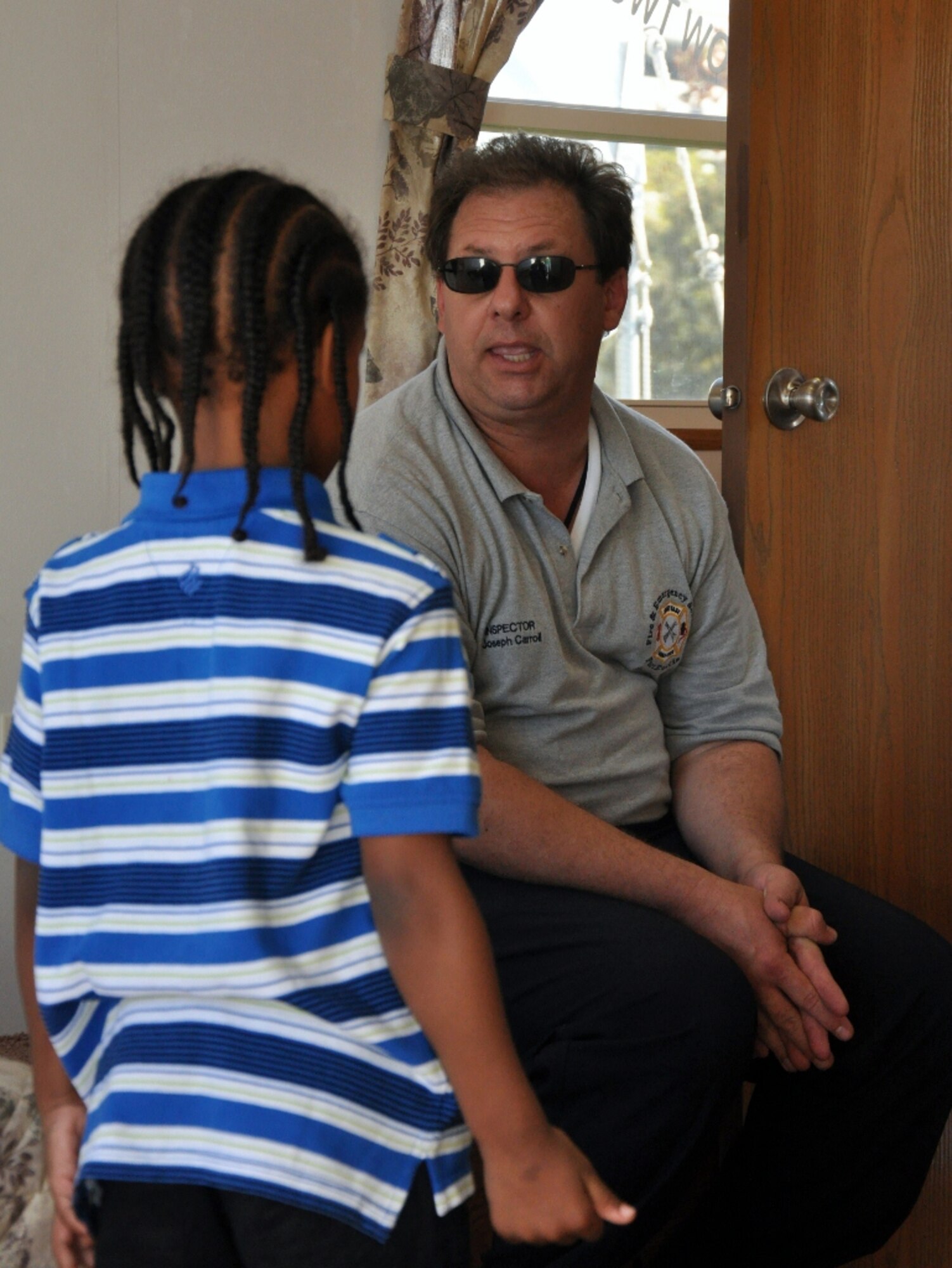 Joseph Carroll, a Fort Eustis Fire Department fire inspector, explains the importance of fire prevention and safety to a young visitor inside the department's fire safety house trailer at the Norfolk Children's Festival at Town Point Park in downtown Norfolk, Va., Oct. 6, 2012. Alongside tours in the trailer, FEFD personnel handed out coloring books, and allowed festival-goers the chance to get an inside look at their specialized “brush truck.” (U.S. Air Force photo by Senior Airman Jason J. Brown/Released)
