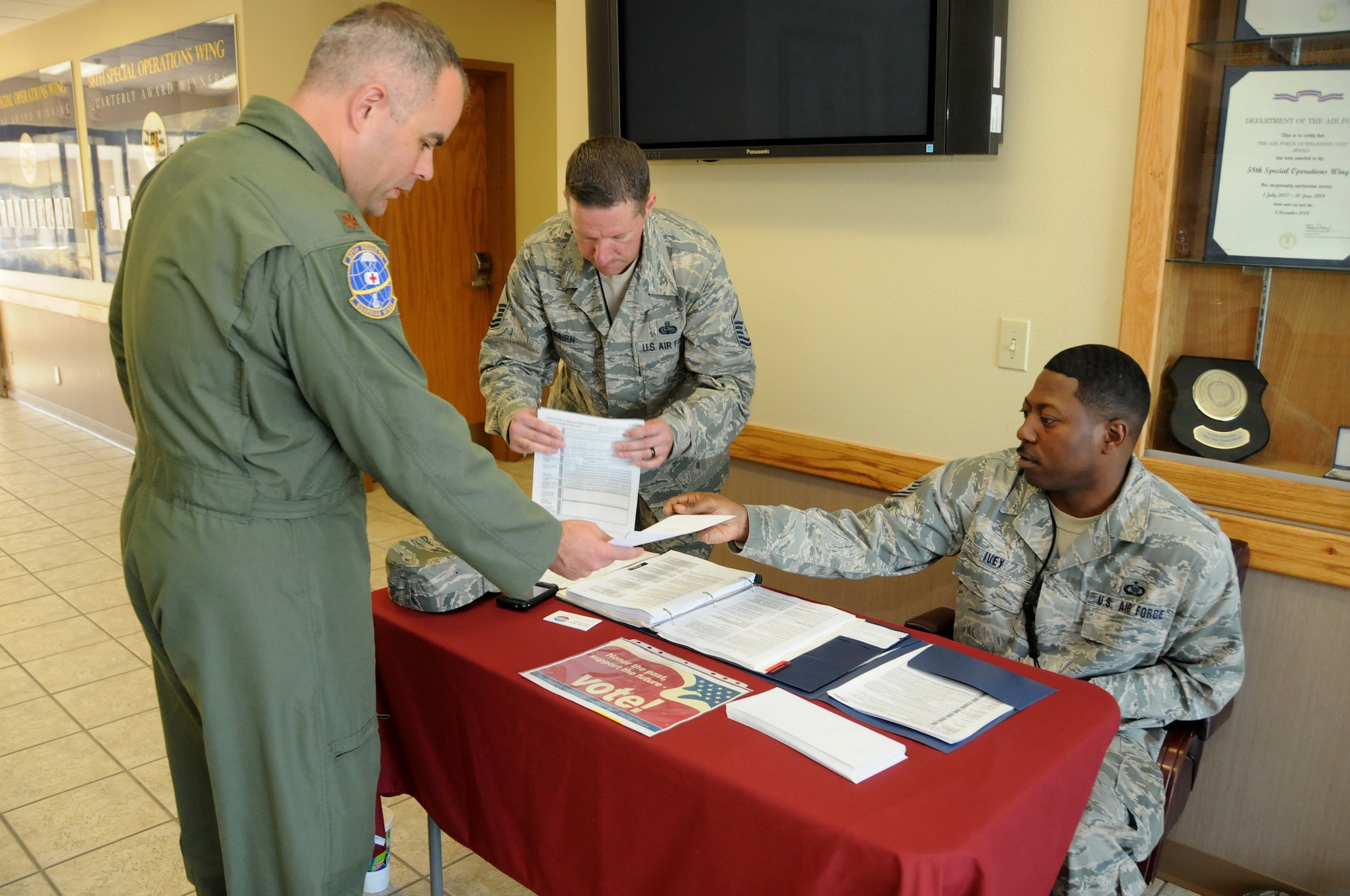 KIRTLAND AFB, N.M. -- Maj. Mike Garner receives voter registration assistance Oct. 3 from Master Sgt. Clifford Nairn and Tech. Sgt. Marcus Ivey. The Department of Defense provides on-base voter registration to increase voter participation. To check the deadline for registration for your state of residence, visit www.fvap.gov. (Photo by Ken Moore)
