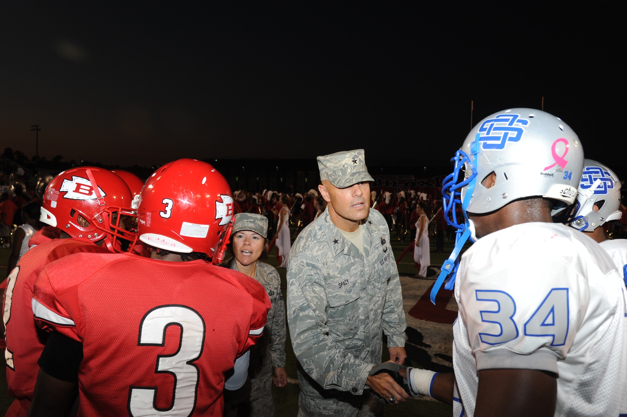 Chief Master Sgt. Angelica Johnson, 81st Training Wing command chief, and Brig. Gen. Brad Spacy, 81st TRW commander, shake the hands of football team captains following the coin toss by Spacy at the Biloxi High School football game against Ocean Springs High School Oct. 5, 2012, at the Biloxi football stadium.  Spacy tossed the coin to determine which team would receive the ball first. Ocean Springs defeated Biloxi 35-34.  (U.S. Air Force photo by Kemberly Groue)