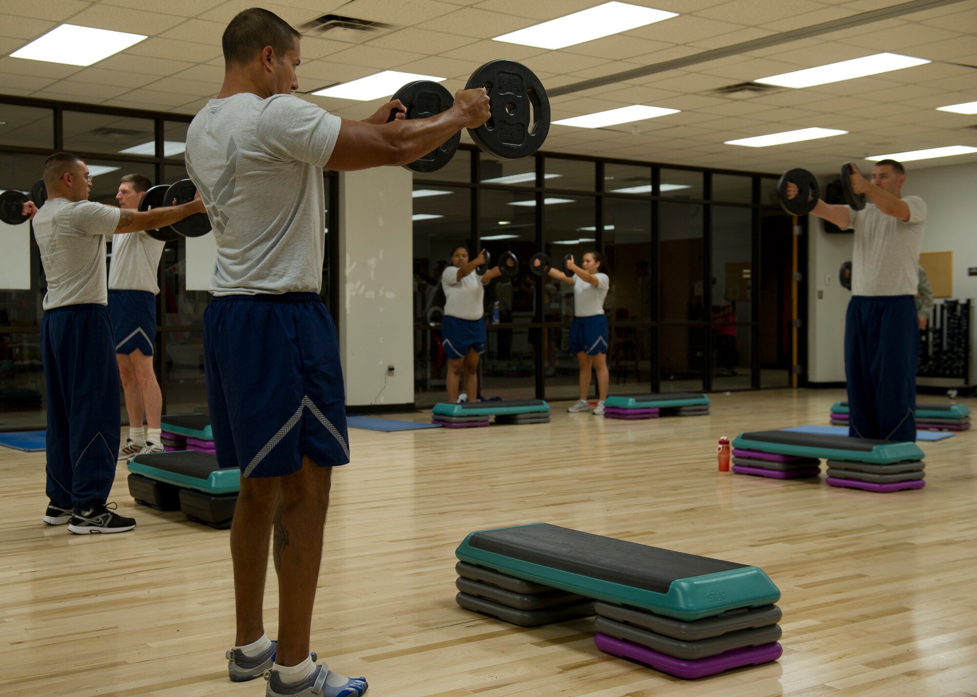 Participants in the Physical Training 101 class perform front deltoid raises during a workout session at Holloman Air Force Base, N.M., Oct. 10. PT 101 is a fitness program that focuses on strength and endurance training and cardio conditioning. Classes are broken down into different components to break up the monotony of doing the same exercises every day and avoid overtraining the participants, which typically stunts progress and can potentially cause injuries. PT 101 is not only designed for people struggling with their PT test, but for all Airmen who need to get into better physical condition. (U.S. Air Force photo by Senior Airman DeAndre Curtiss/Released)